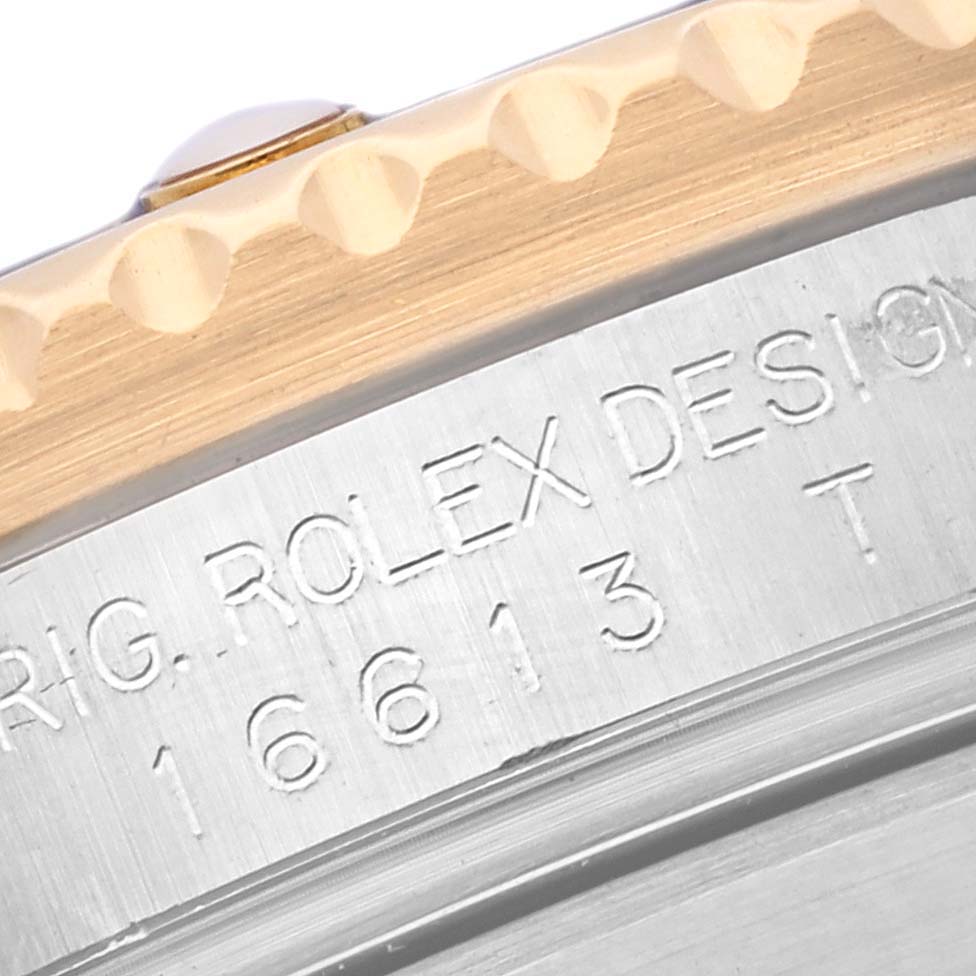 The image shows a close-up of the Rolex Submariner 16613 Men's Steel and Gold (two tone) Blue Dial 16613 Men's Steel and Gold (two tone) Blue Dial's engraved case side and bezel edge.