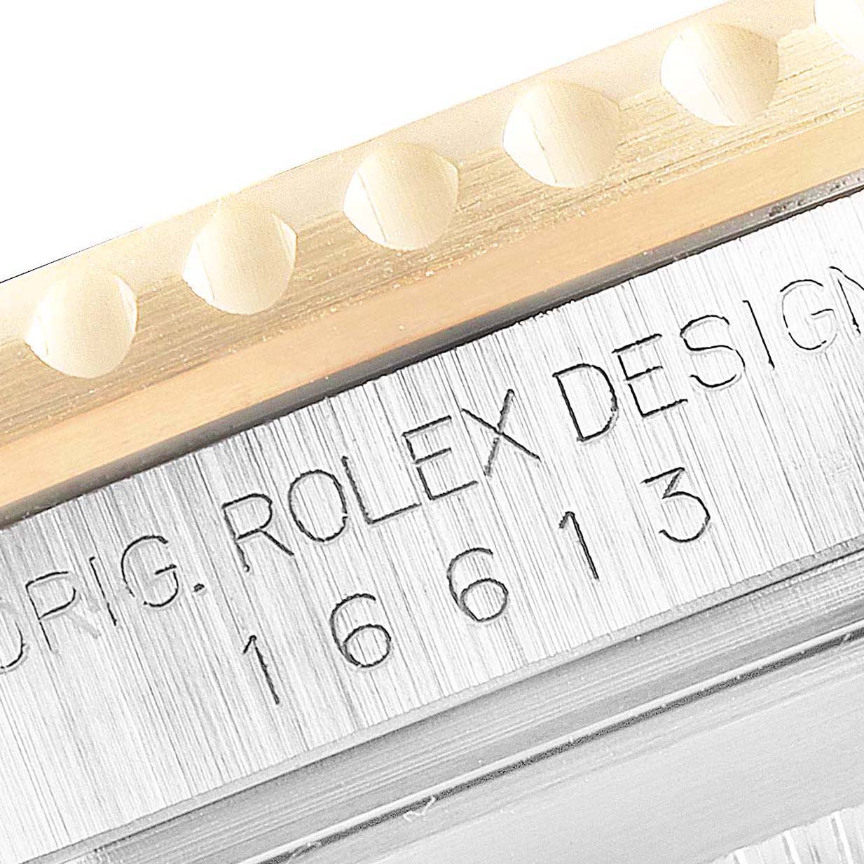 The image shows a close-up of a Rolex Submariner 16613 Men's Steel and Gold (two tone) Blue Dial 16613 Men's Steel and Gold (two tone) Blue Dial model's bezel and engraved serial number on the side.