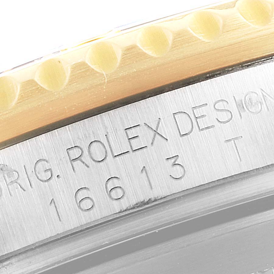 This close-up image shows the engraved side bezel of a Rolex Submariner 16613 Men's Steel and Gold (two tone) Champagne Dial 16613 Men's Steel and Gold (two tone) Champagne Dial, including the model number and branding.