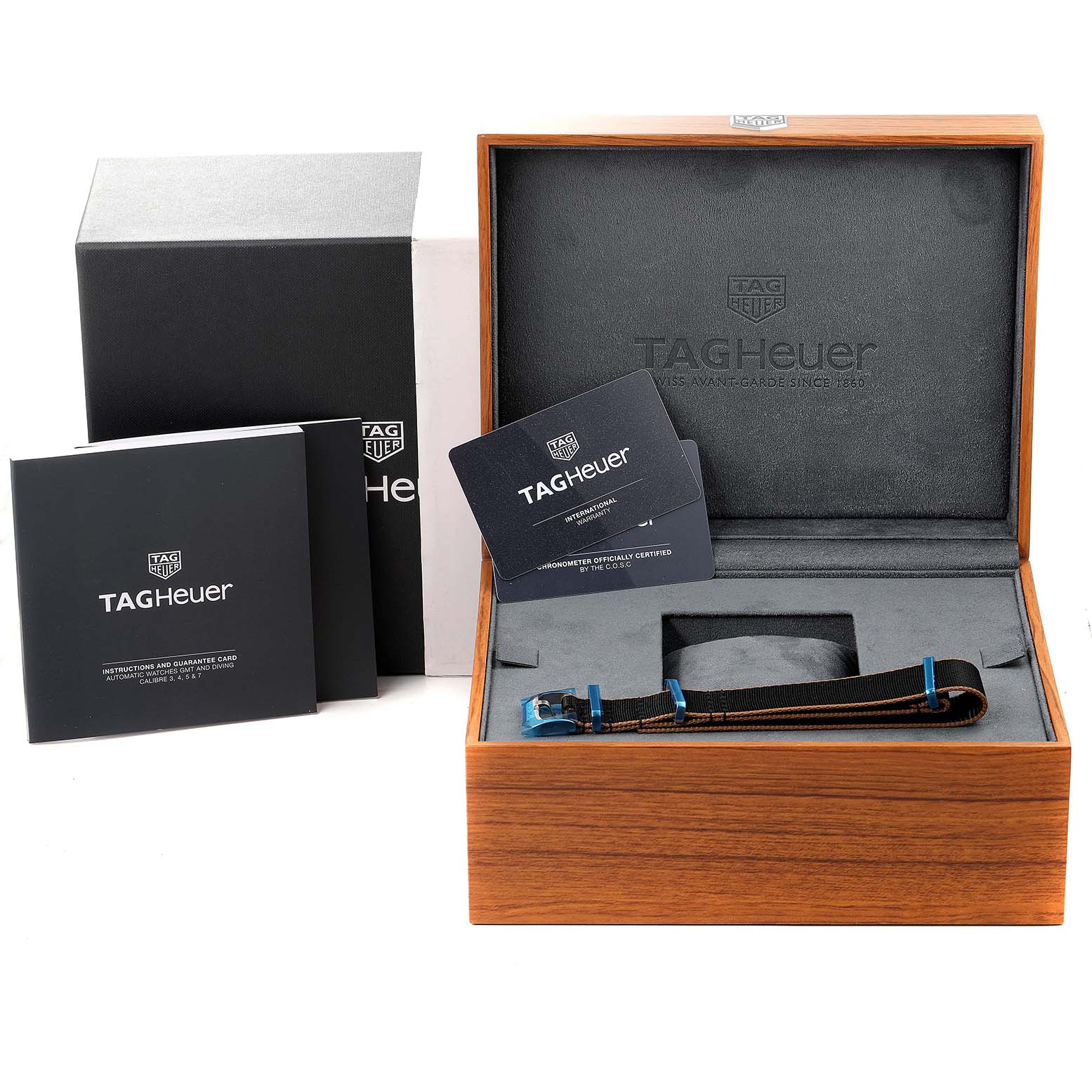 The image shows a Tag Heuer Autavia WBE5114.EB0173 Men's Stainless Steel Brown Dial WBE5114.EB0173 Men's Stainless Steel Brown Dial watch box, a strap, and instruction booklets, all viewed from a straight angle.