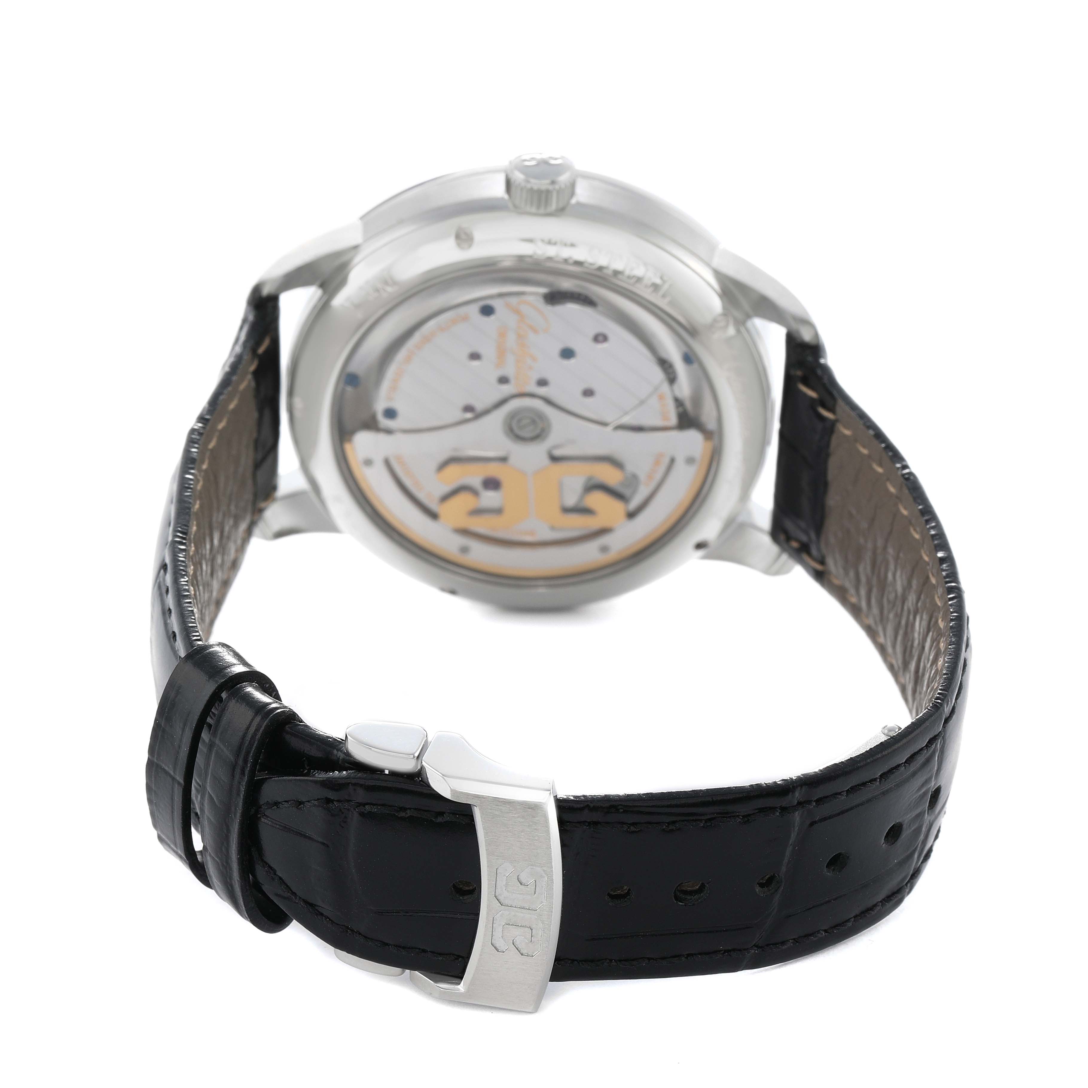 The Glashütte Pano watch is shown from the back, revealing its transparent case back and movement, with its leather strap visible.