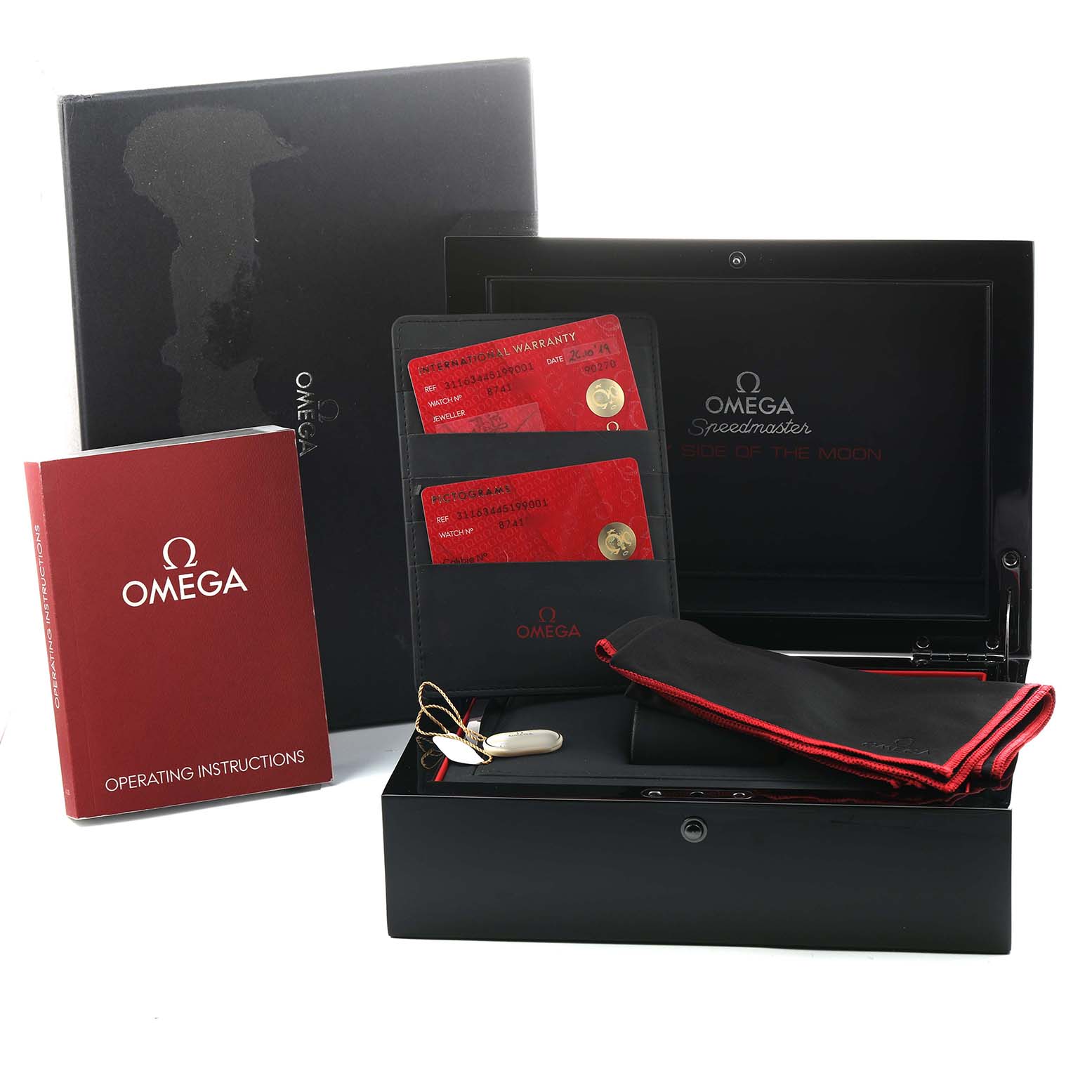 The Omega Speedmaster 311.63.44.51.99.001 Men's Ceramic Grey Dial packaging includes a box, warranty cards, instructions, and a cloth, viewed from above.