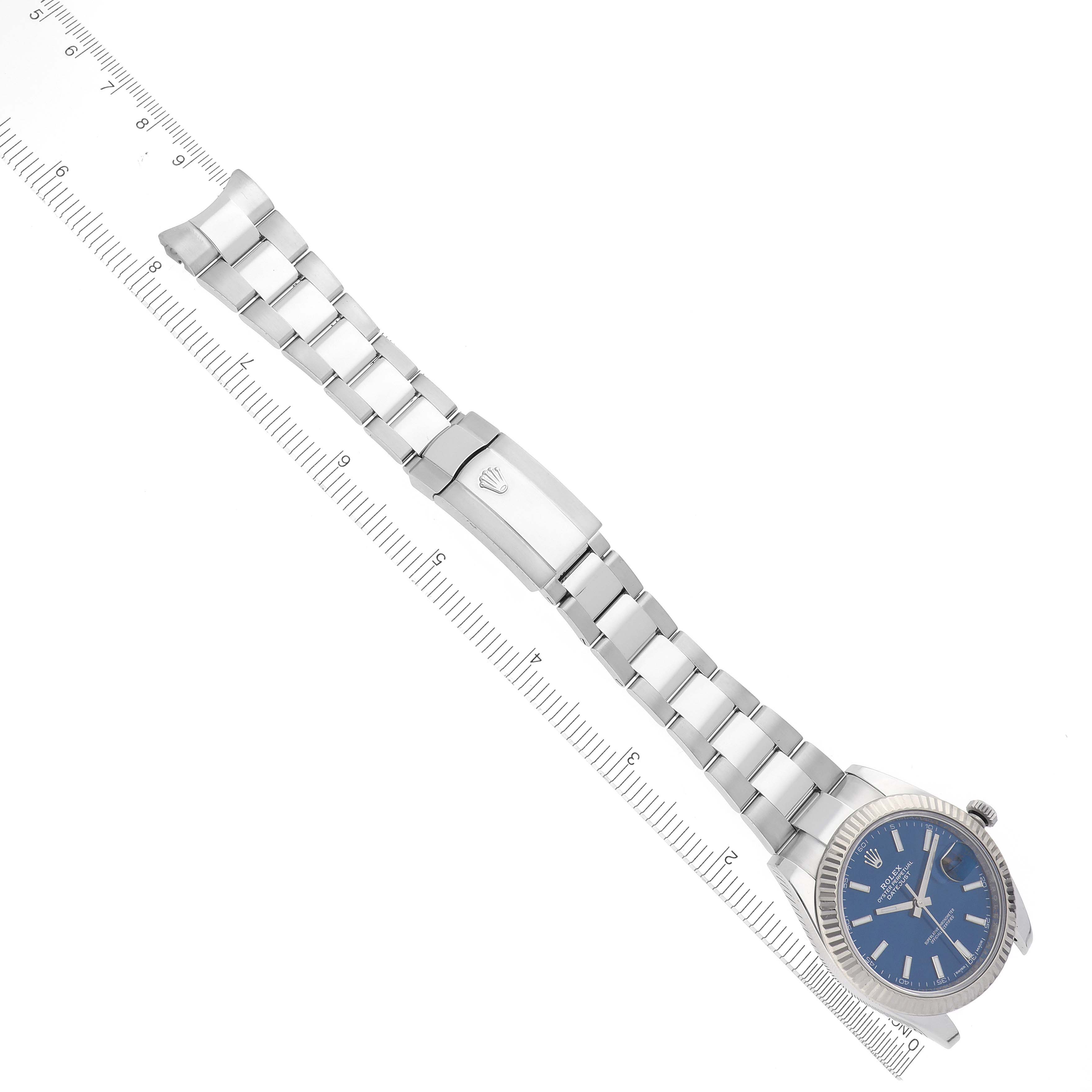 The Rolex Datejust 41 126334 Men's Stainless Steel Blue Dial 126334 Men's Stainless Steel Blue Dial is shown diagonally from the front, displaying the full bracelet and clasp next to a ruler.