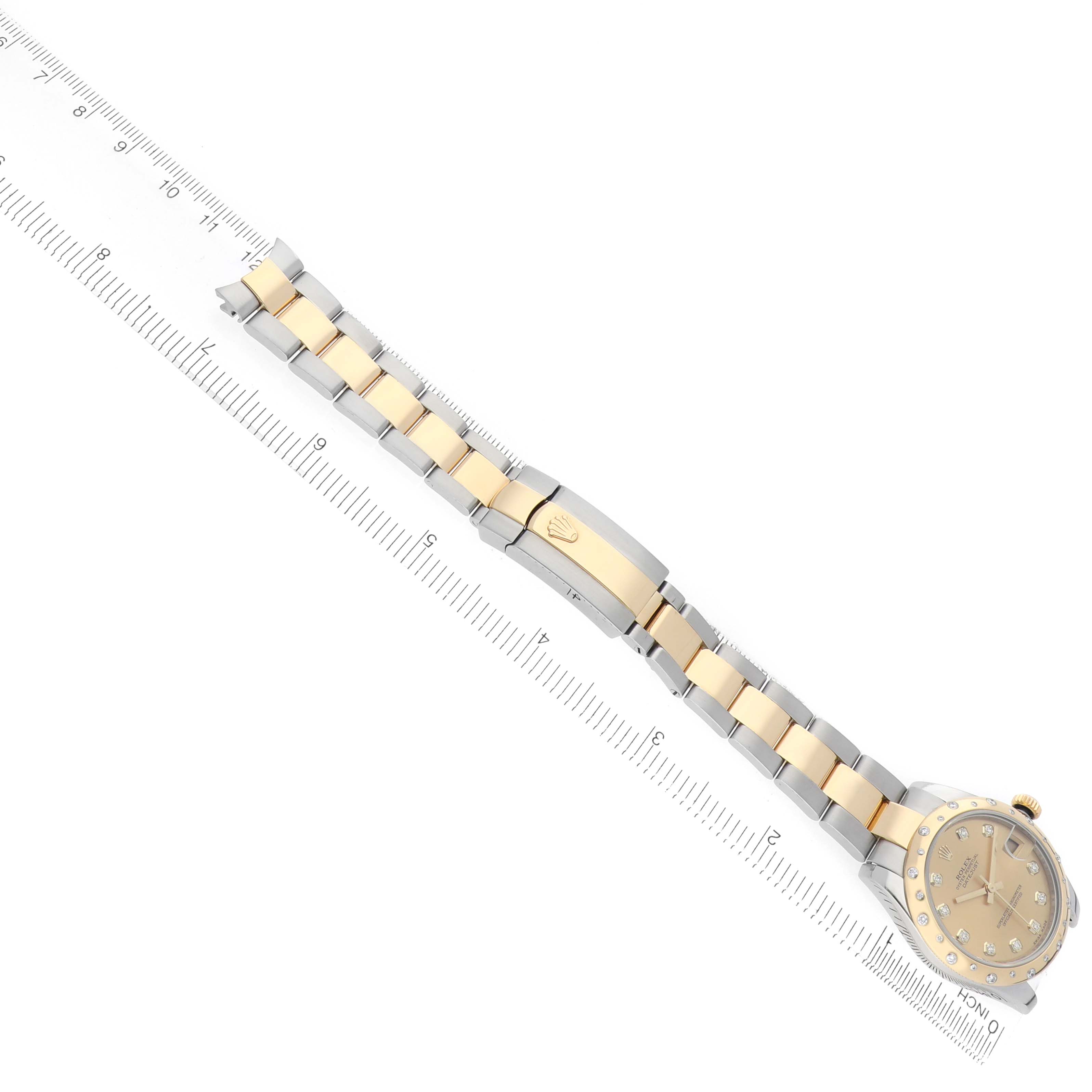 The Rolex Mid-Size 178343 Women's Steel and Gold (two tone) Champagne Dial watch is shown at an angle, displaying the entire bracelet and clasp alongside a ruler for scale.