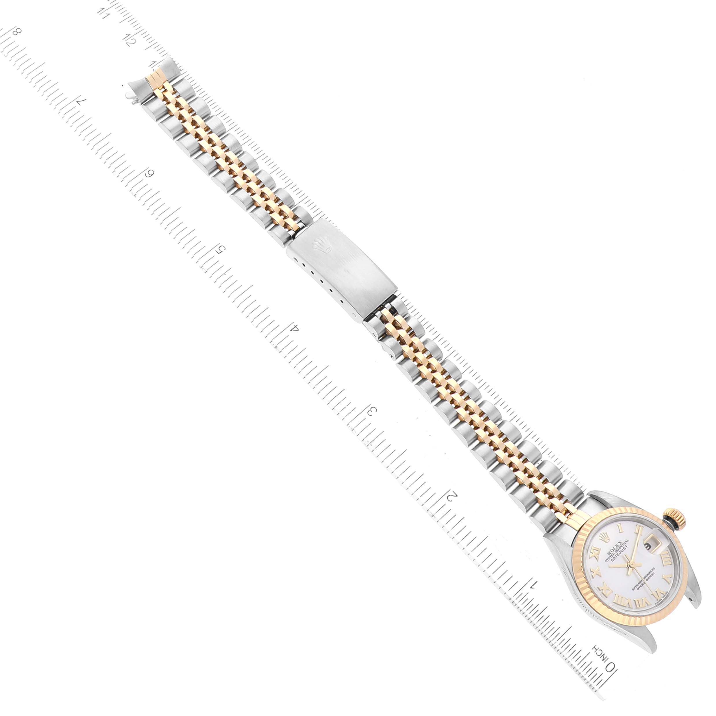 The Rolex Datejust 79173 Women's Steel and Gold (two tone) Mother of Pearl Dial 79173 Women's Steel and Gold (two tone) Mother of Pearl Dial watch is shown from above, highlighting its face, gold bezel, stainless steel, and gold bracelet with a ruler beneath.