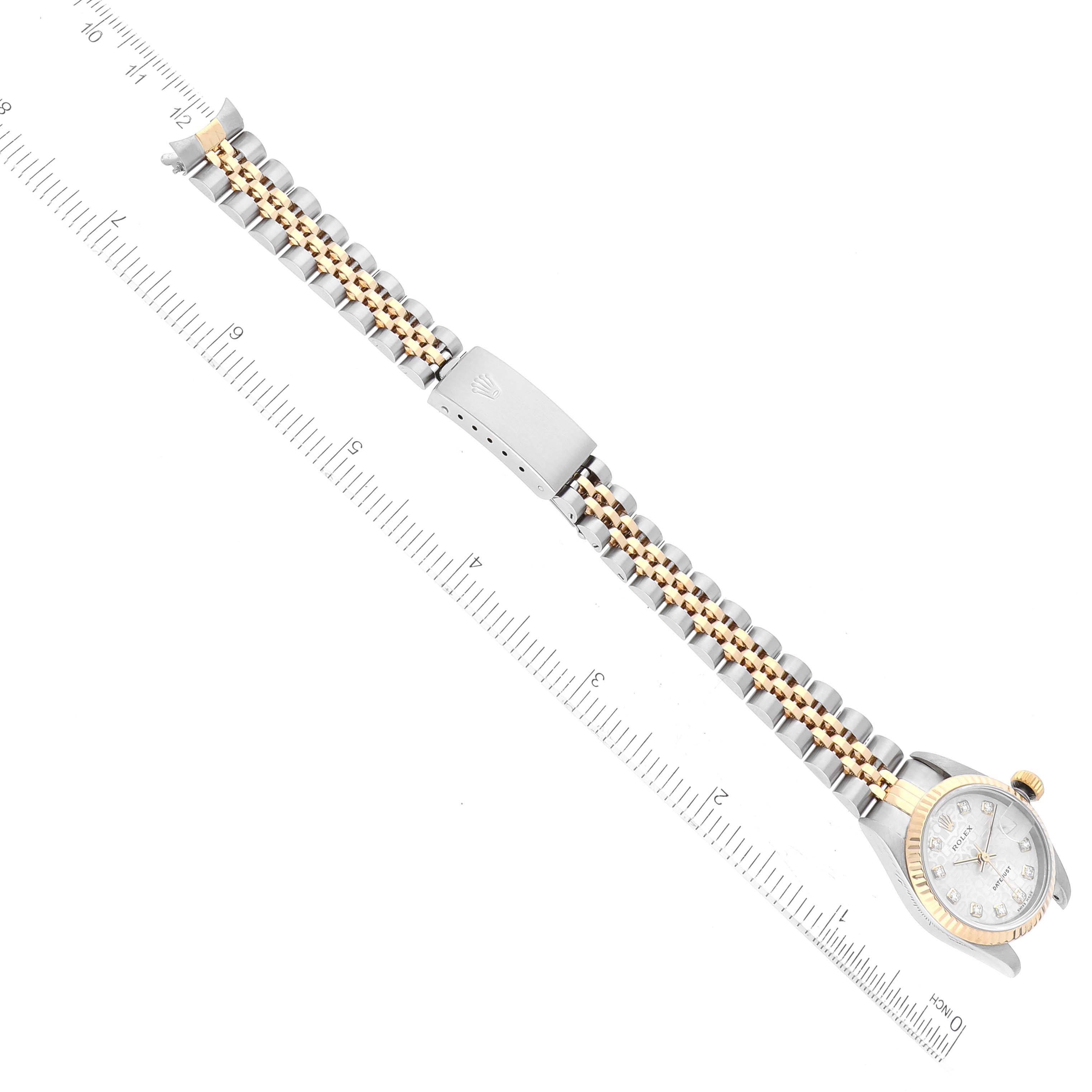 This image shows a Rolex Datejust 79173G Women's Steel and Gold (two tone) Silver Dial 79173G Women's Steel and Gold (two tone) Silver Dial model watch laid flat with the band extended and aligned next to a ruler for scale.