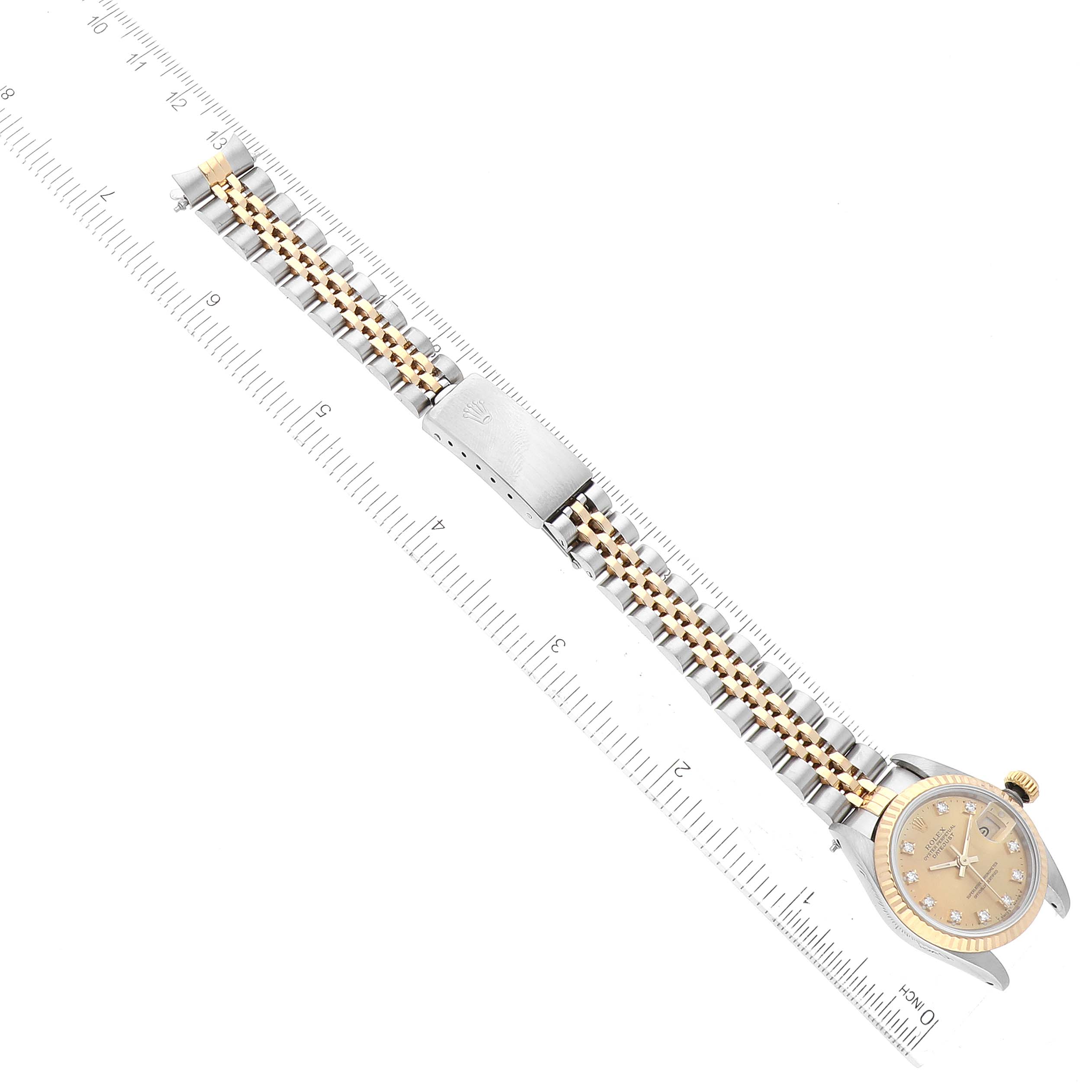 This image shows a Rolex Datejust 69173 Women's Steel and Gold (two tone) Champagne Dial 69173 Women's Steel and Gold (two tone) Champagne Dial watch laid flat, with its bracelet aligned along a measuring scale.