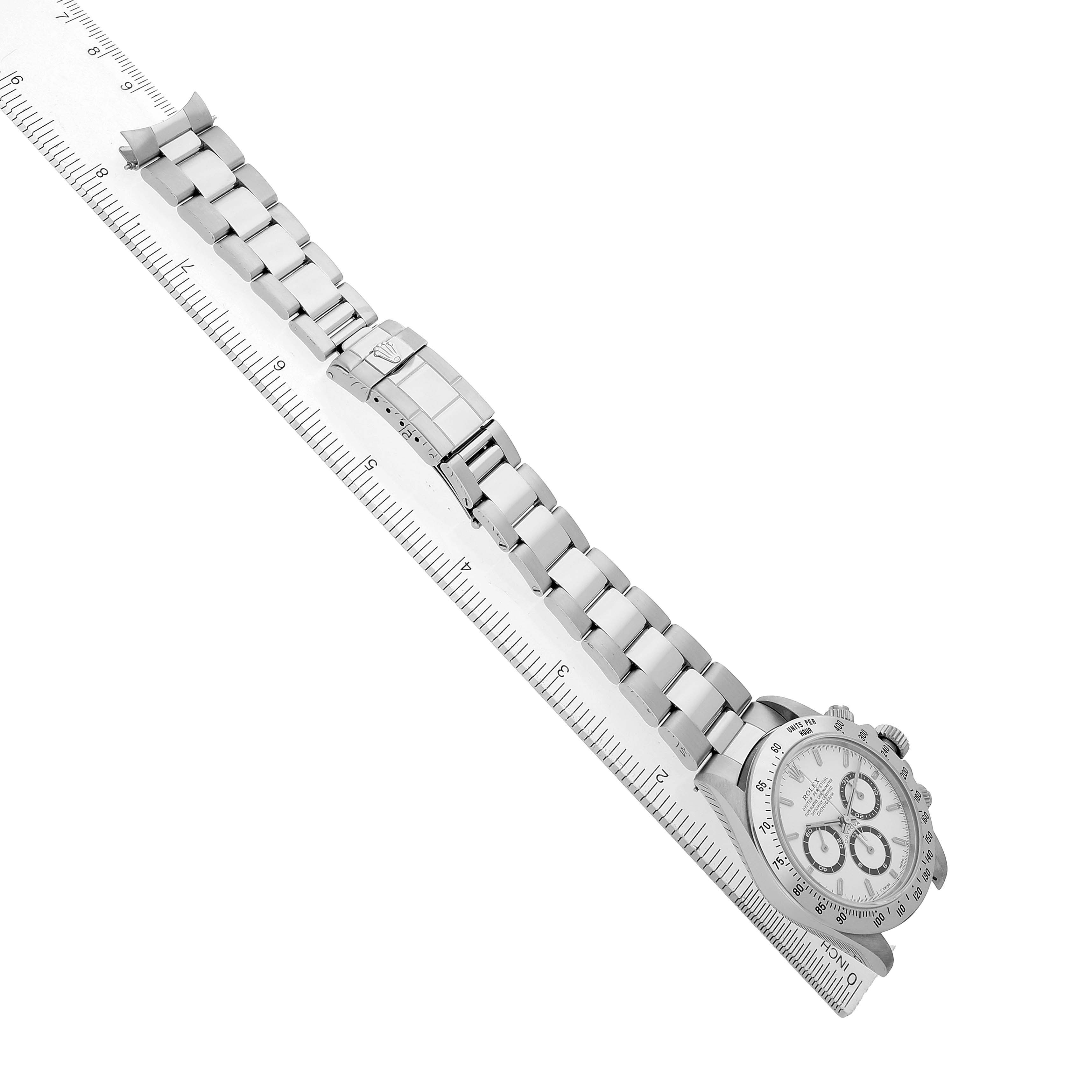The Rolex Daytona 16520 Men's Stainless Steel White Dial watch is shown from a top angle, displaying the bracelet, clasp, and face alongside a ruler for size reference.