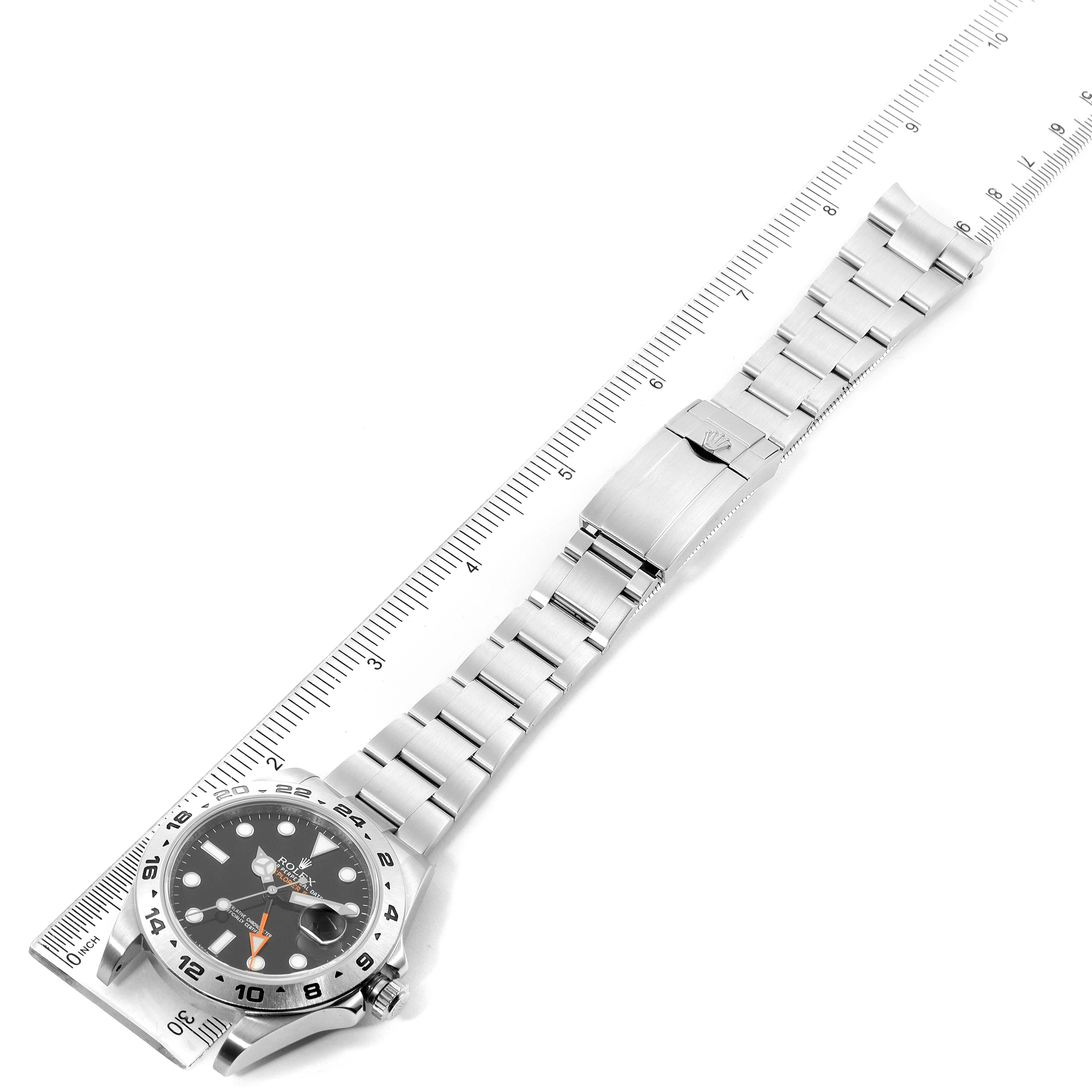 This image shows a top-down view of a Rolex Explorer 216570 Men
s Stainless Steel Black Dial 216570 Men
s Stainless Steel Black Dial watch, including its face, bezel, bracelet, and clasp, along with a measuring tape.