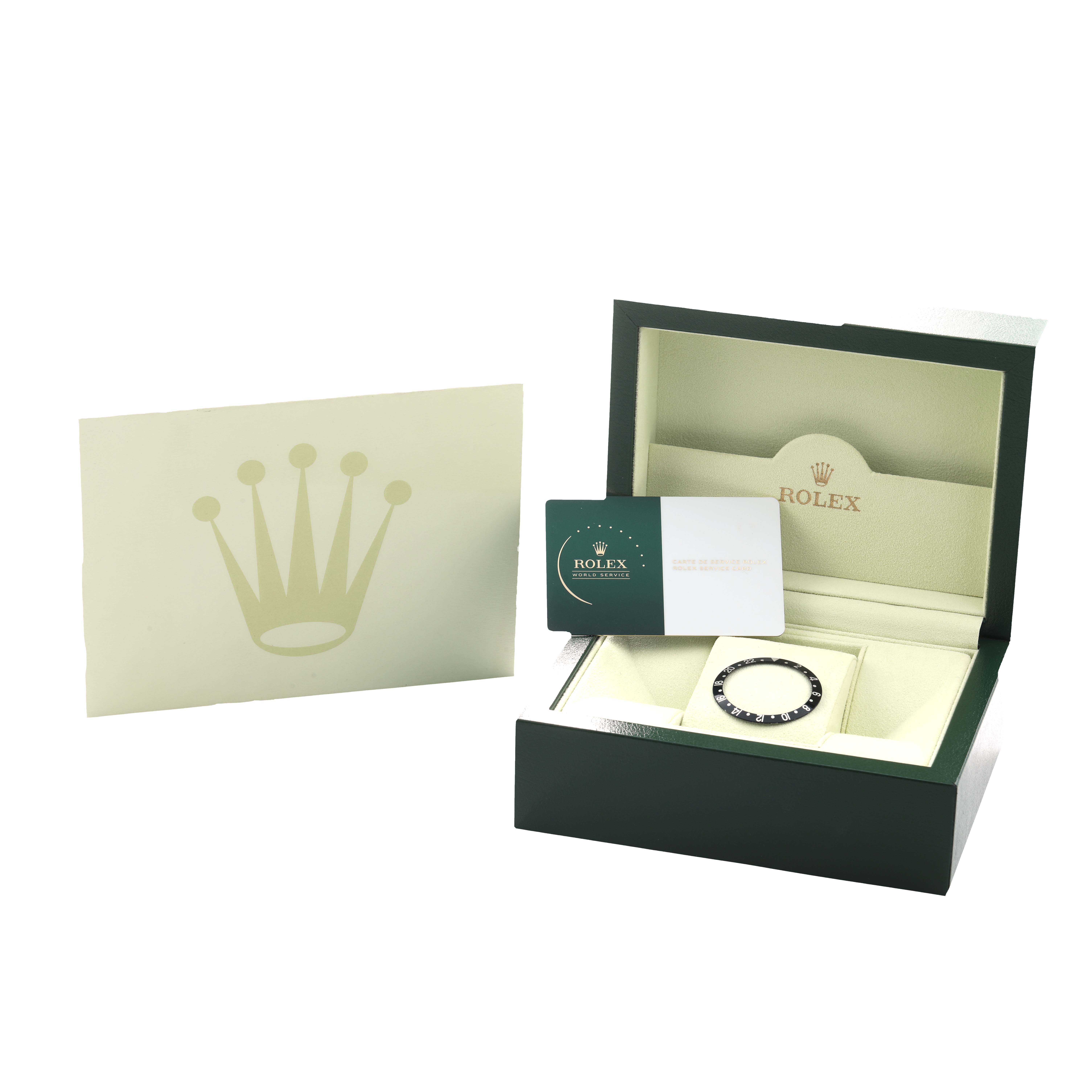 The image shows a Rolex GMT-Master 16710 Men's Stainless Steel Black Dial watch bezel and certificate inside an open box, with the logo visible on the packaging.