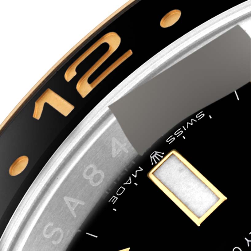 This close-up image of a Rolex GMT-Master 126713 Men's Steel and Gold (two tone) Black Dial 126713 Men's Steel and Gold (two tone) Black Dial watch displays part of the bezel, numerals, and a segment of the watch dial.