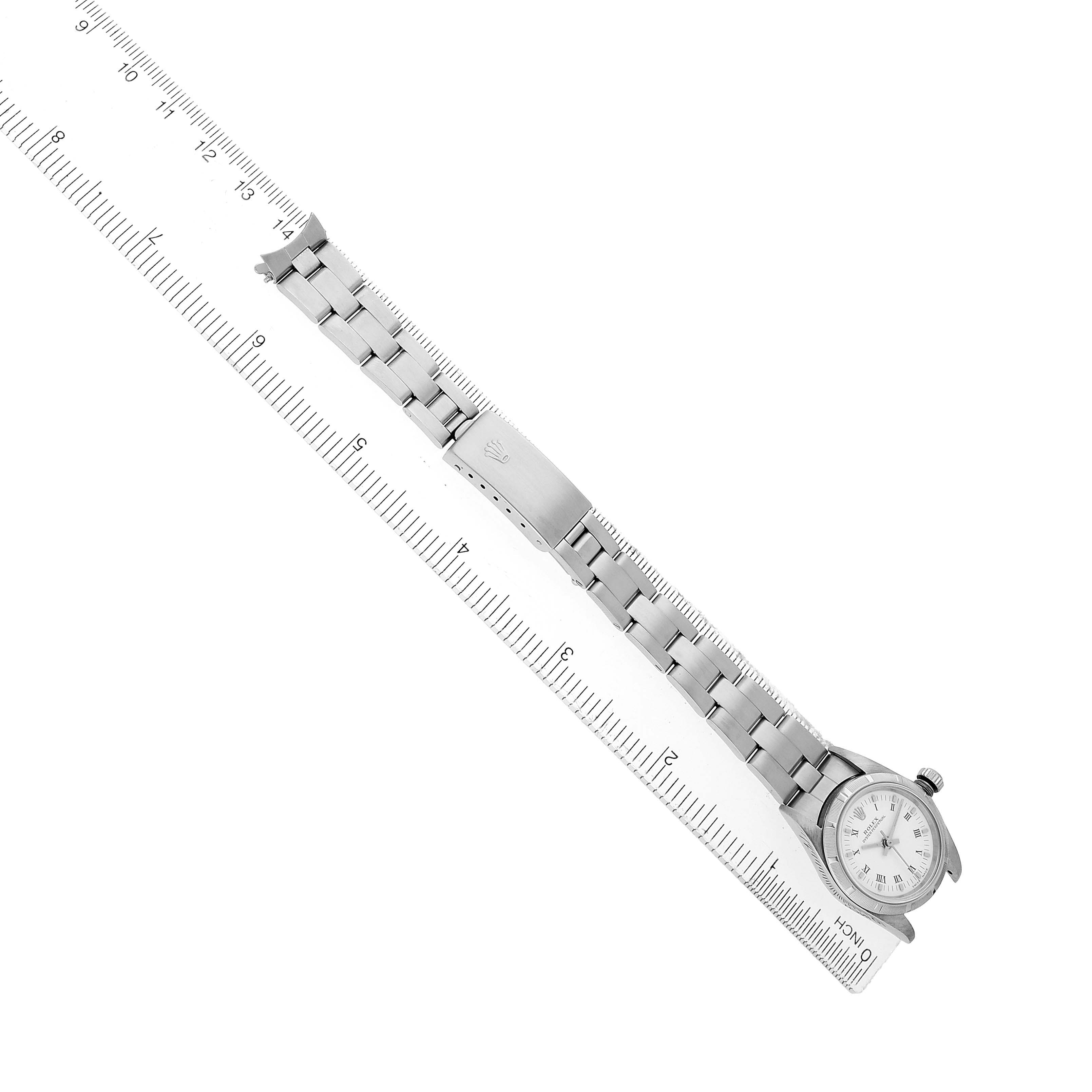 The Rolex Oyster Perpetual 76030 Women's Stainless Steel White Dial is shown at a slight angle, displaying its face, bracelet, and clasp alongside a ruler for size reference.