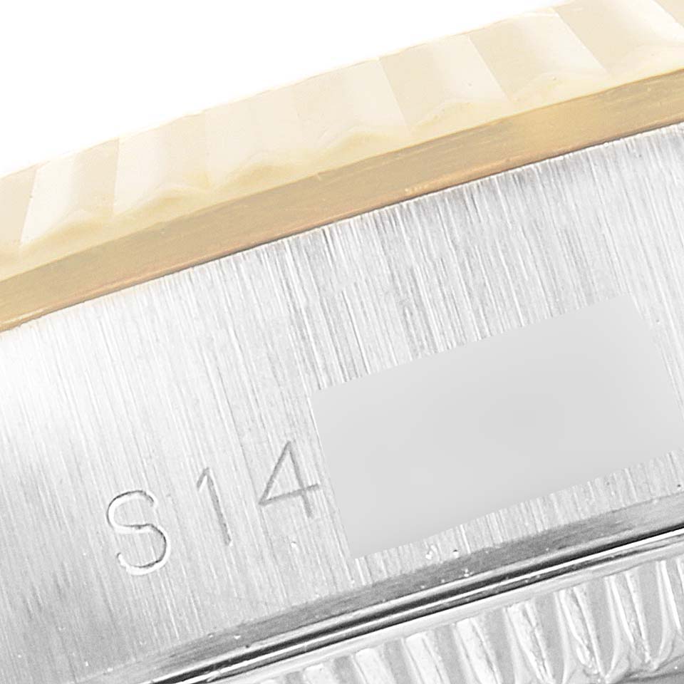 The image shows a close-up of the side of the Rolex Oyster Perpetual 67193 Women
s Steel and Gold (two tone) Black Dial 67193 Women
s Steel and Gold (two tone) Black Dial watch, focusing on the edge of the bezel and part of the serial number.
