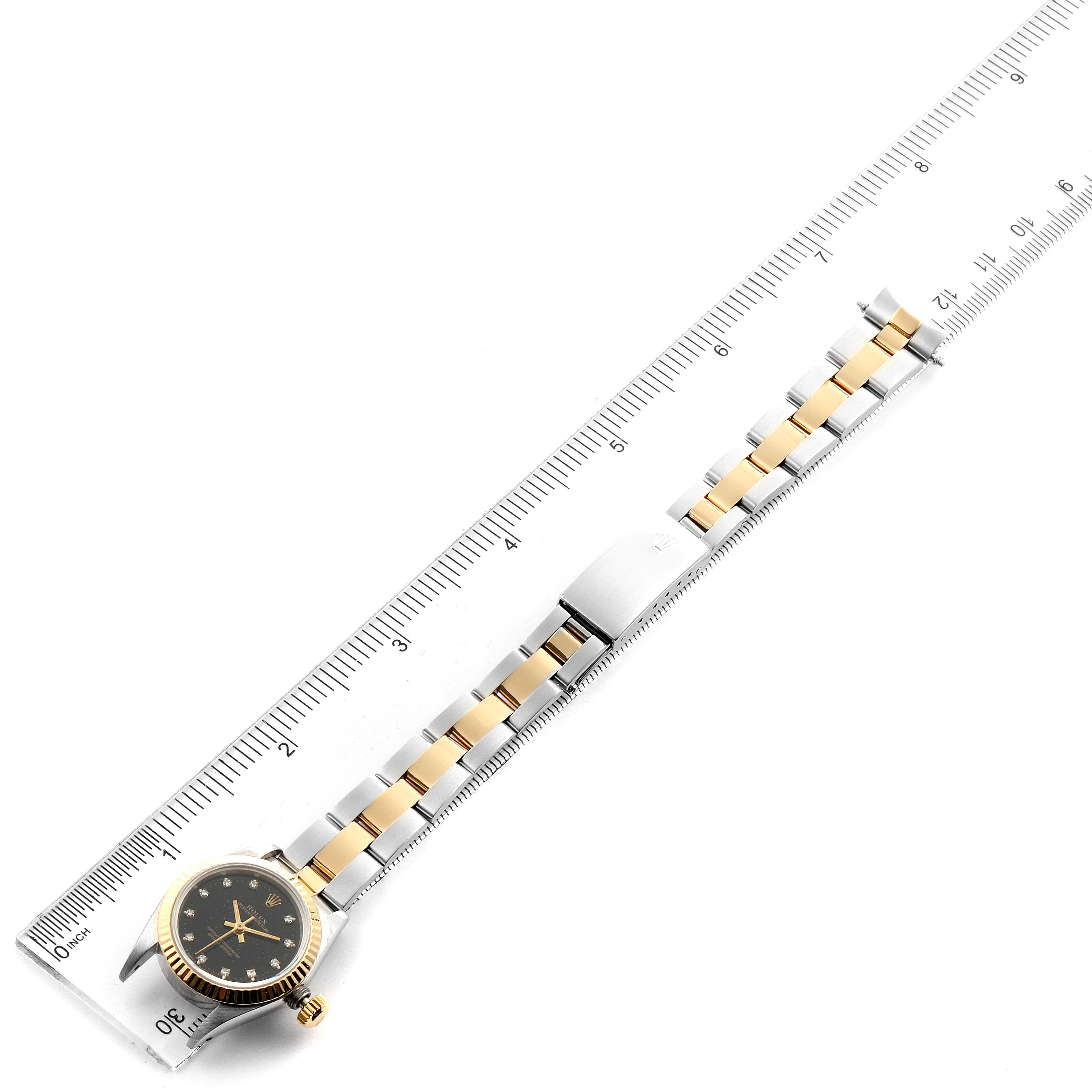 The image shows a Rolex Oyster Perpetual 67193 Women
s Steel and Gold (two tone) Black Dial 67193 Women
s Steel and Gold (two tone) Black Dial watch laid flat with a ruler measuring its length, including the band and face.