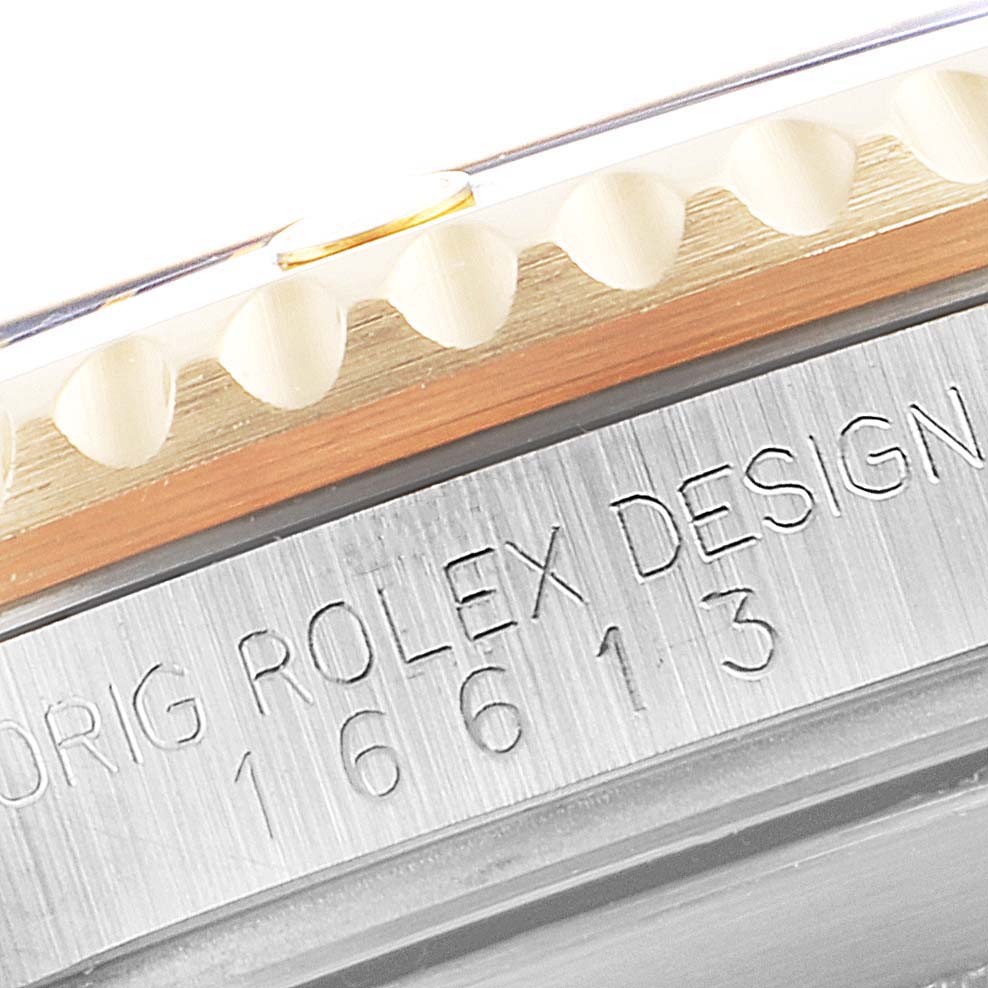 This close-up image of a Rolex Submariner 16613 Men's Steel and Gold (two tone) Blue Dial 16613 Men's Steel and Gold (two tone) Blue Dial watch shows the engraved model number and part of the bezel's edge.