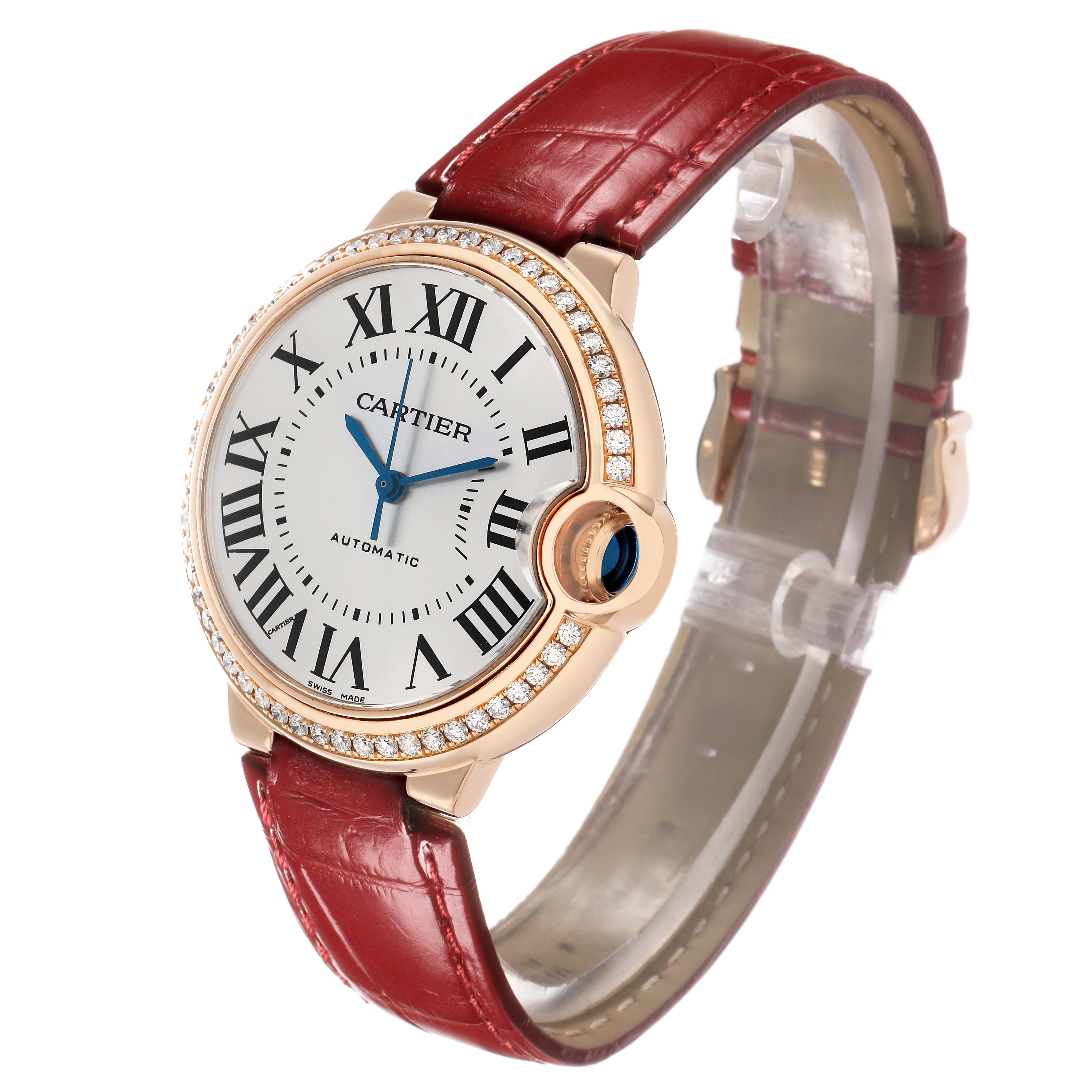 The Ballon Bleu de Cartier watch is shown from a three-quarter angle, highlighting its red strap, diamond bezel, and blue hands.