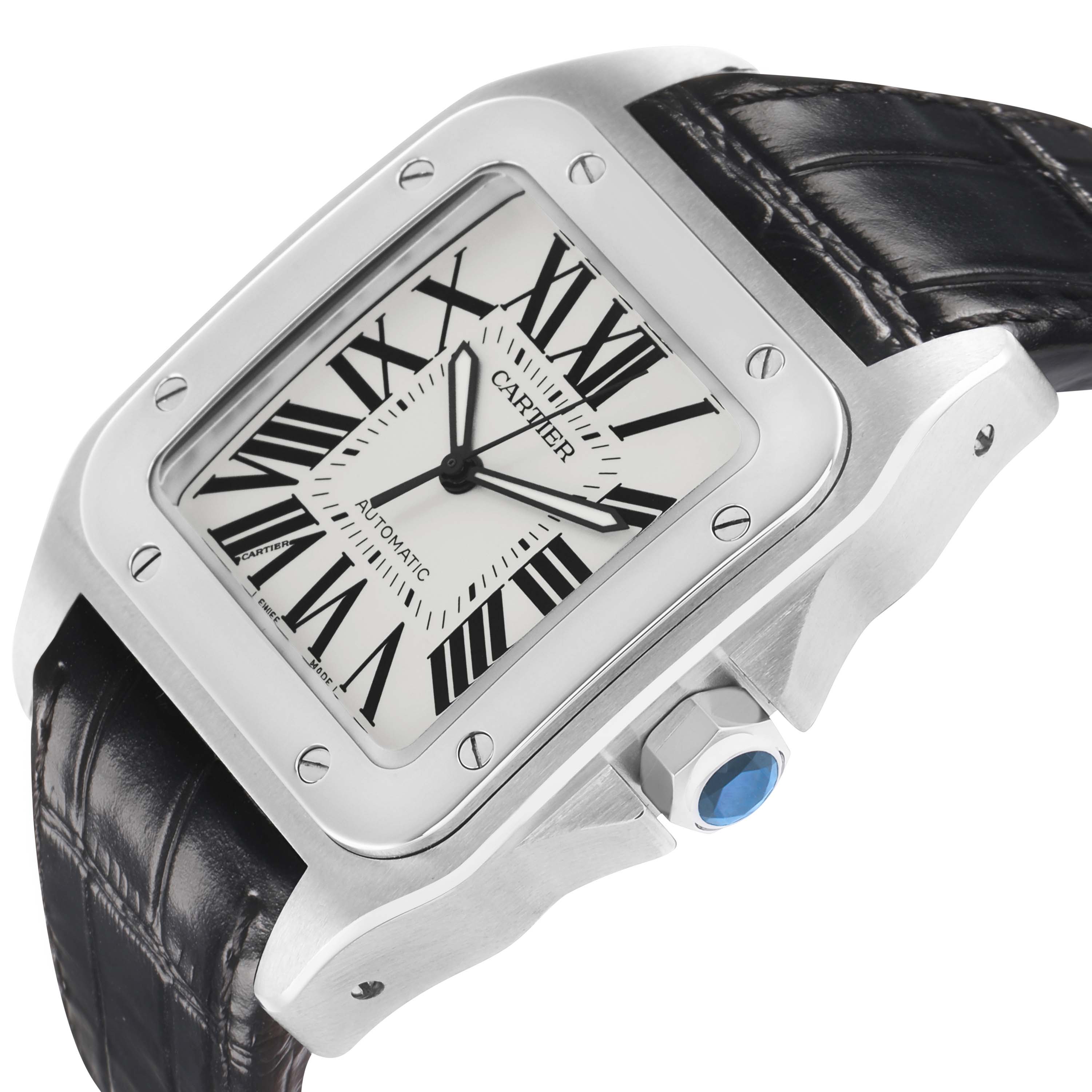 The Cartier Santos W20073X8 Men's Stainless Steel Silver Dial watch is angled to show the face, bezel with screws, crown with a blue gem, and part of the leather strap.
