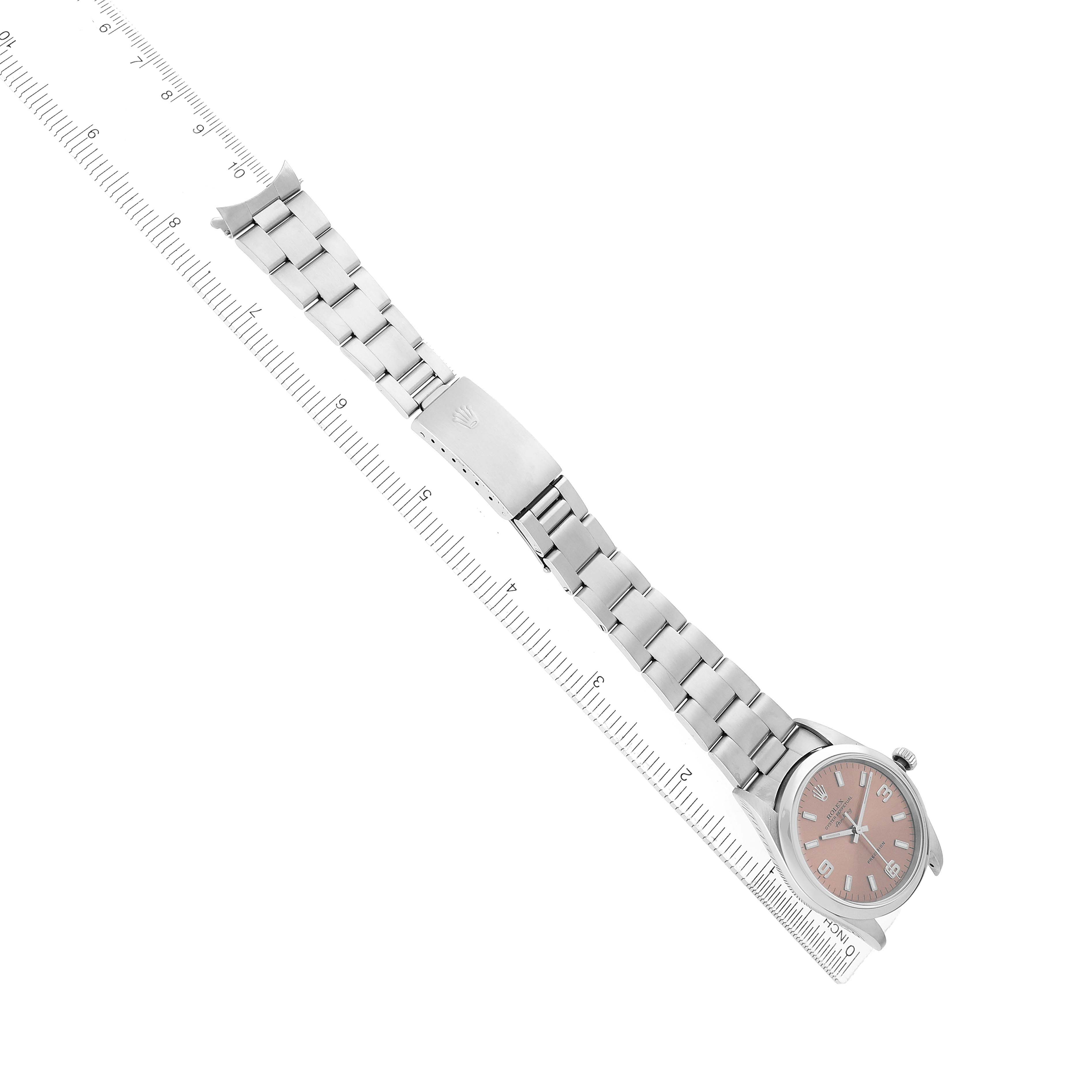 The Rolex Air-King 14000 Men's Stainless Steel Pink Dial watch is shown at an overhead angle, displaying its bracelet, clasp, and face beside a ruler for scale.