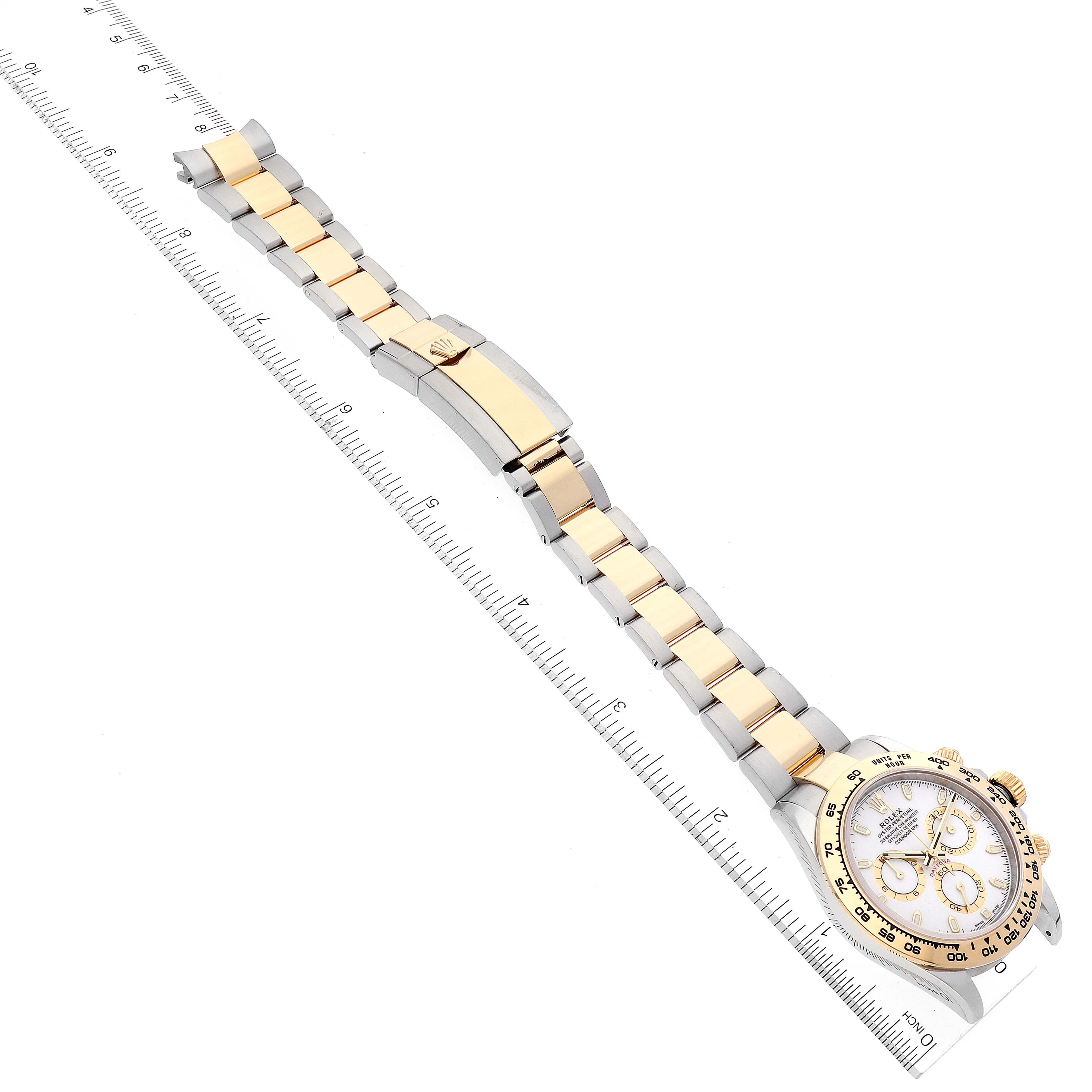 The Rolex Daytona 116503 Men's Steel and Gold (two tone) White Dial 116503 Men's Steel and Gold (two tone) White Dial watch is shown from a top-down angle, displaying the face, bezel, and full bracelet alongside a ruler for scale.