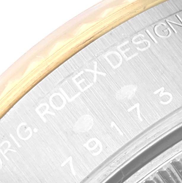 This close-up image shows the case side and part of the bezel of a Rolex Datejust 79173G Women's Steel and Gold (two tone) White Dial 79173G Women's Steel and Gold (two tone) White Dial watch, revealing engraved text.