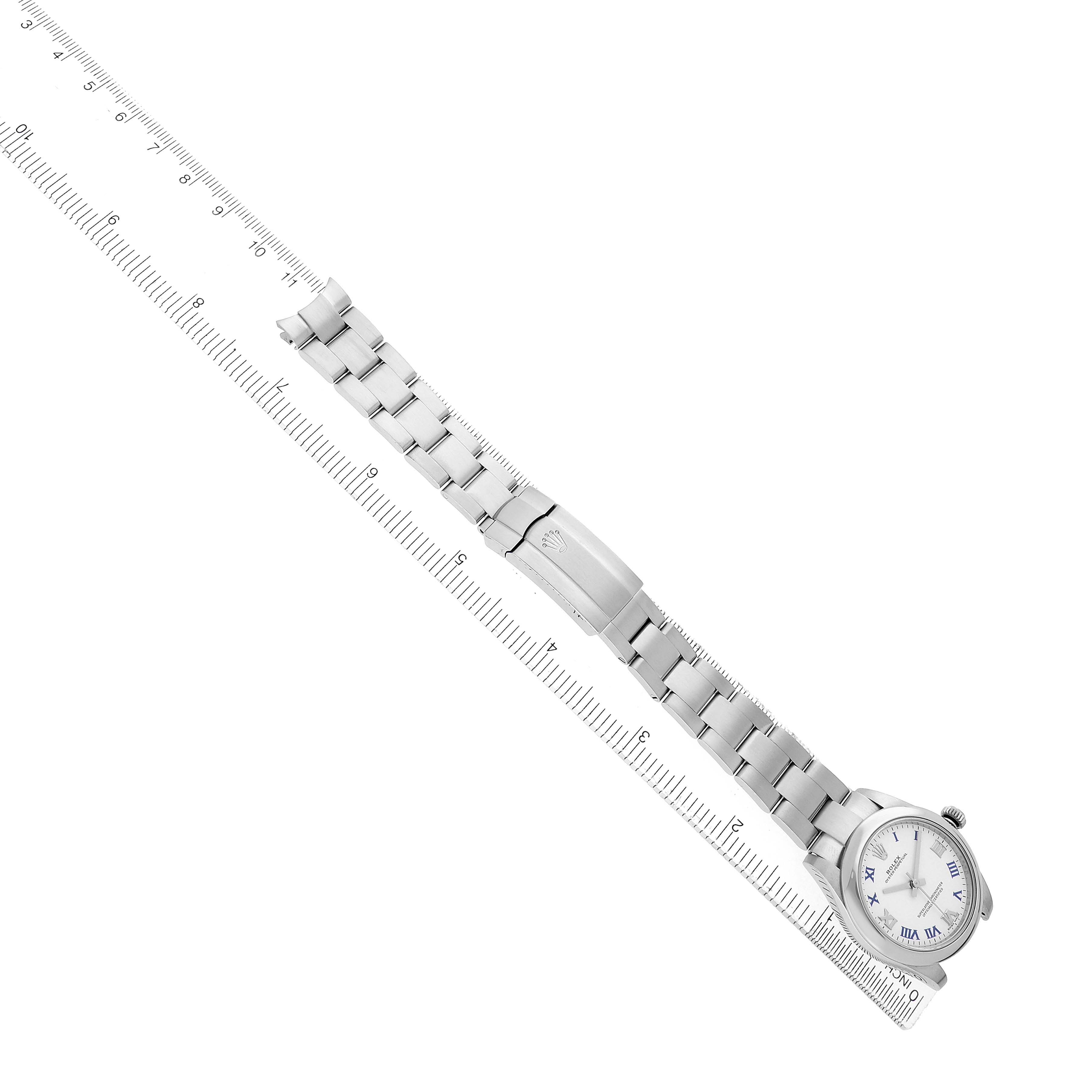 The Rolex Mid-Size 177200 Women's Stainless Steel White Dial model watch is shown from an overhead angle, displaying the face, bracelet, and clasp next to a ruler.