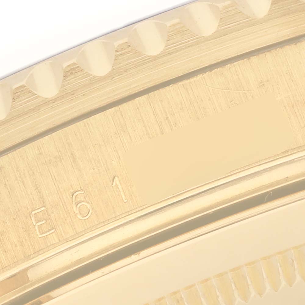 The image shows a close-up of the gold bezel edge and part of the serial number of a Rolex Submariner 16618 Men's Yellow Gold Blue Dial 16618 Men's Yellow Gold Blue Dial.