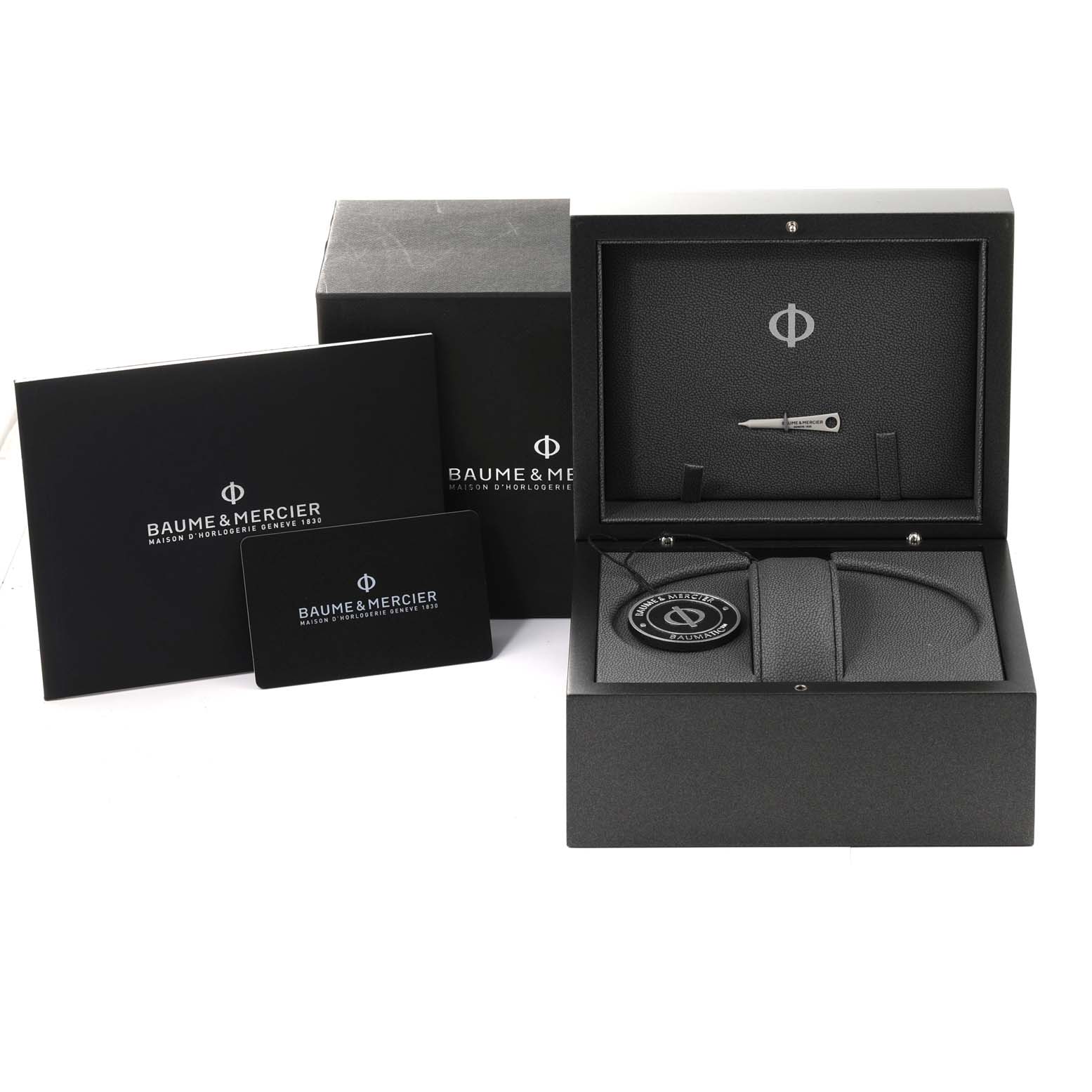 The image shows the packaging of a Baume 
Mercier Clifton M0A10548 Men
s Stainless Steel Grey Dial M0A10548 Men
s Stainless Steel Grey Dial watch, including the box, booklet, card, and a small tool.