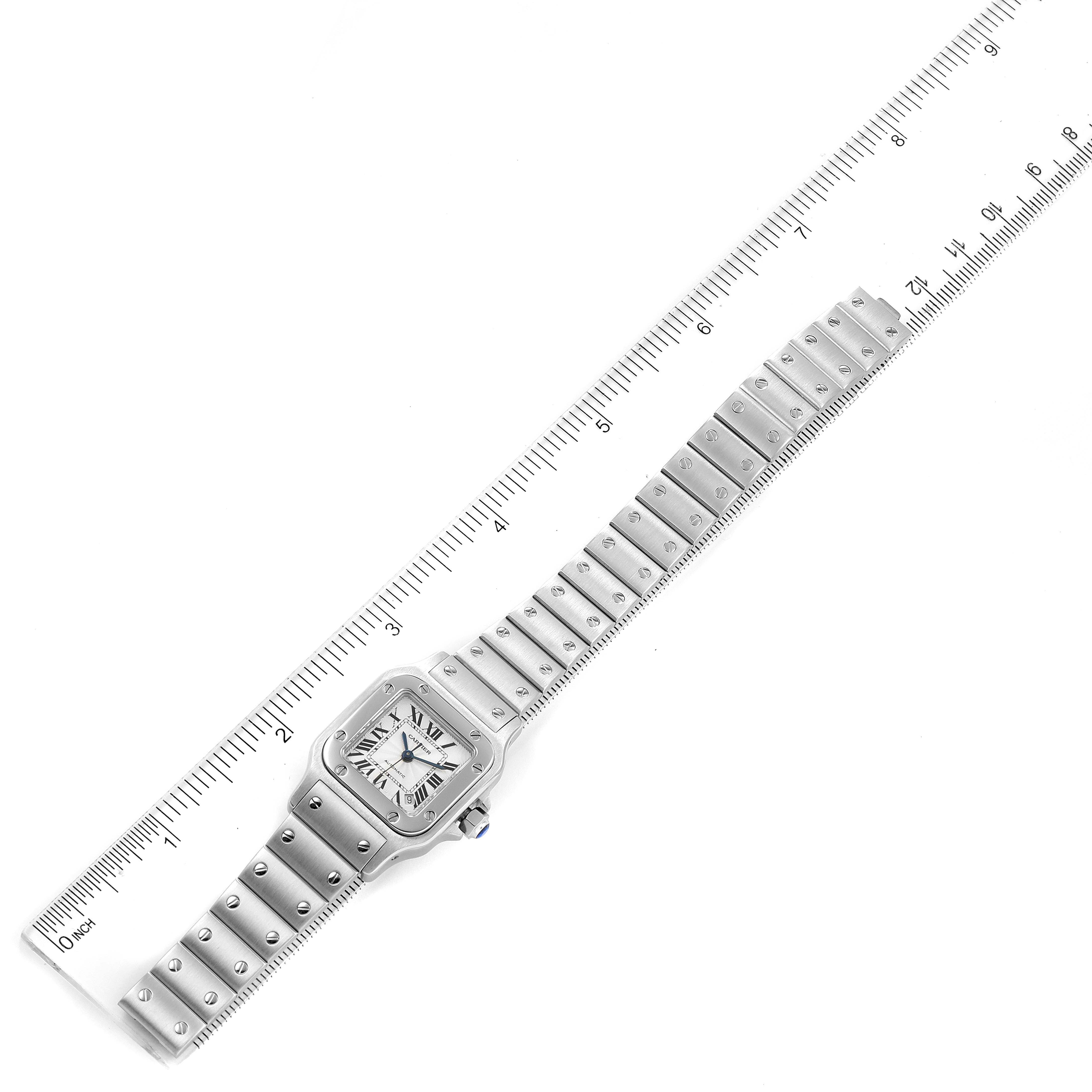 The image shows a top-down view of a Cartier Santos W20044D6 Women's Stainless Steel Silver Dial W20044D6 Women's Stainless Steel Silver Dial watch with its full metal band alongside a ruler for scale.