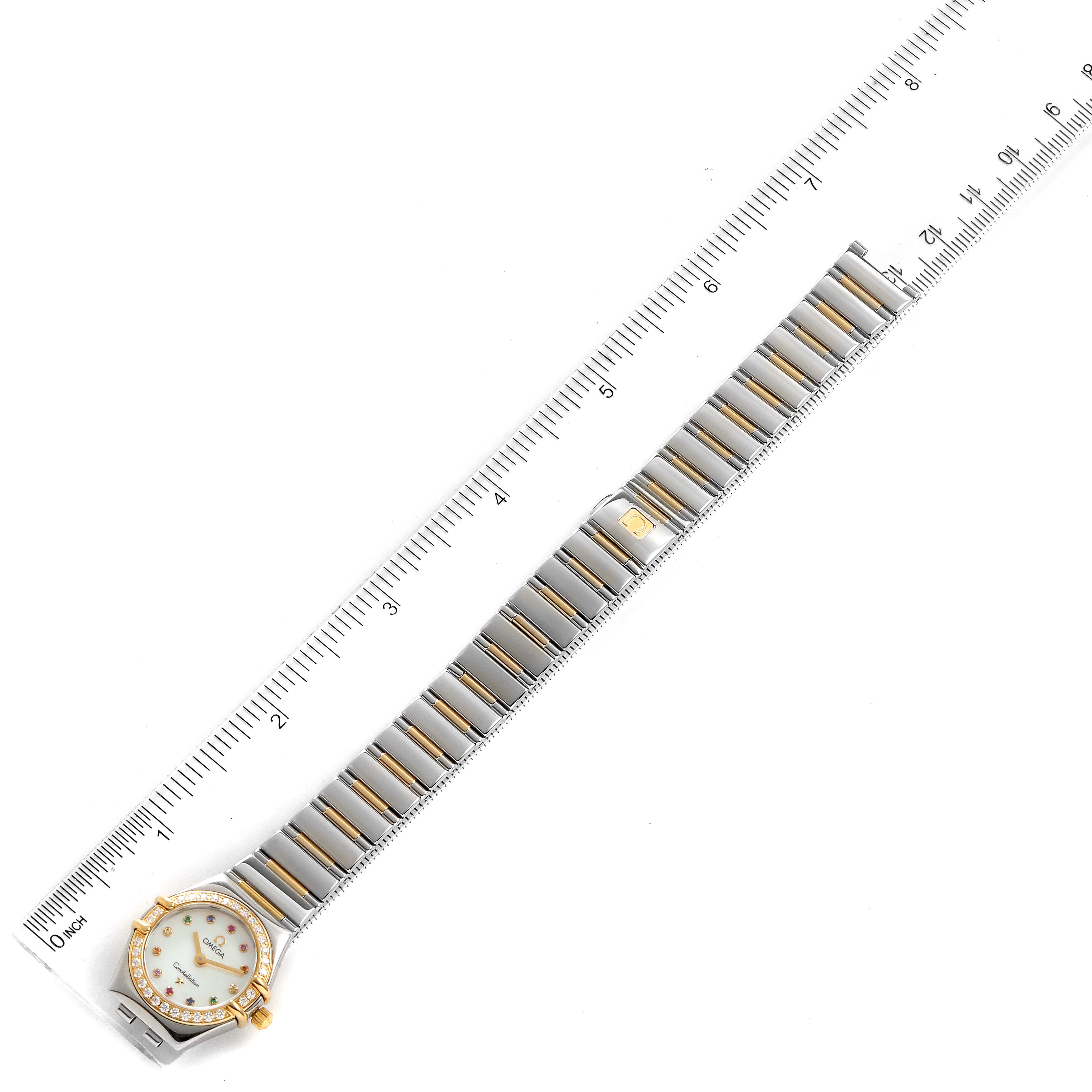 The Omega 1365.79.00 Women's Steel and Gold (two tone) Mother of Pearl Dial 1365.79.00 Women's Steel and Gold (two tone) Mother of Pearl Dial Constellation Iris Steel Yellow Gold Multi Stone Watch 1365.79.00 is shown from an overhead perspective, displaying the entire watch alongside a ruler.