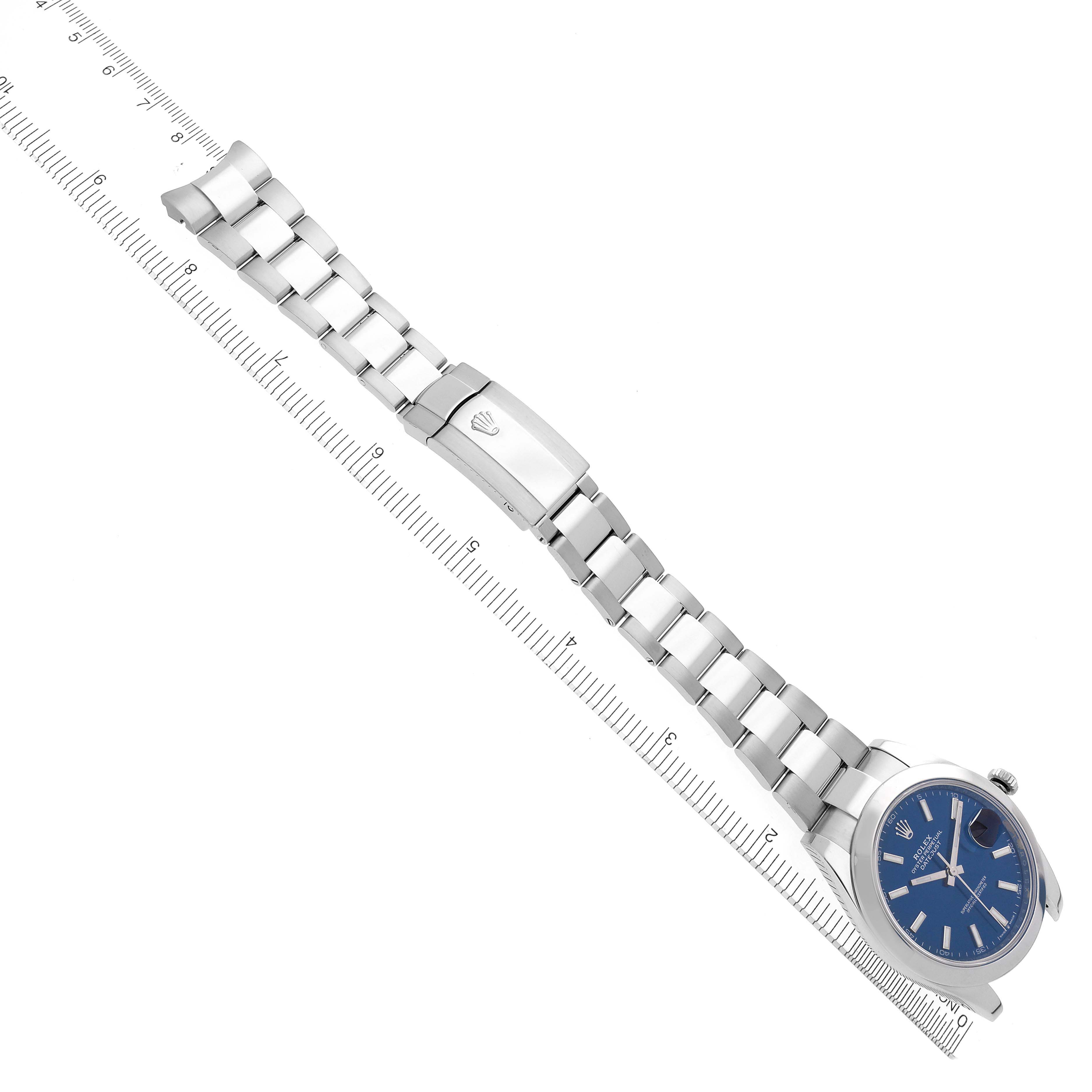 The image shows a Rolex Datejust 41 126300 Men's Stainless Steel Blue Dial 126300 Men's Stainless Steel Blue Dial watch lying flat, highlighting the bracelet, clasp, and blue dial at an angle with a ruler.
