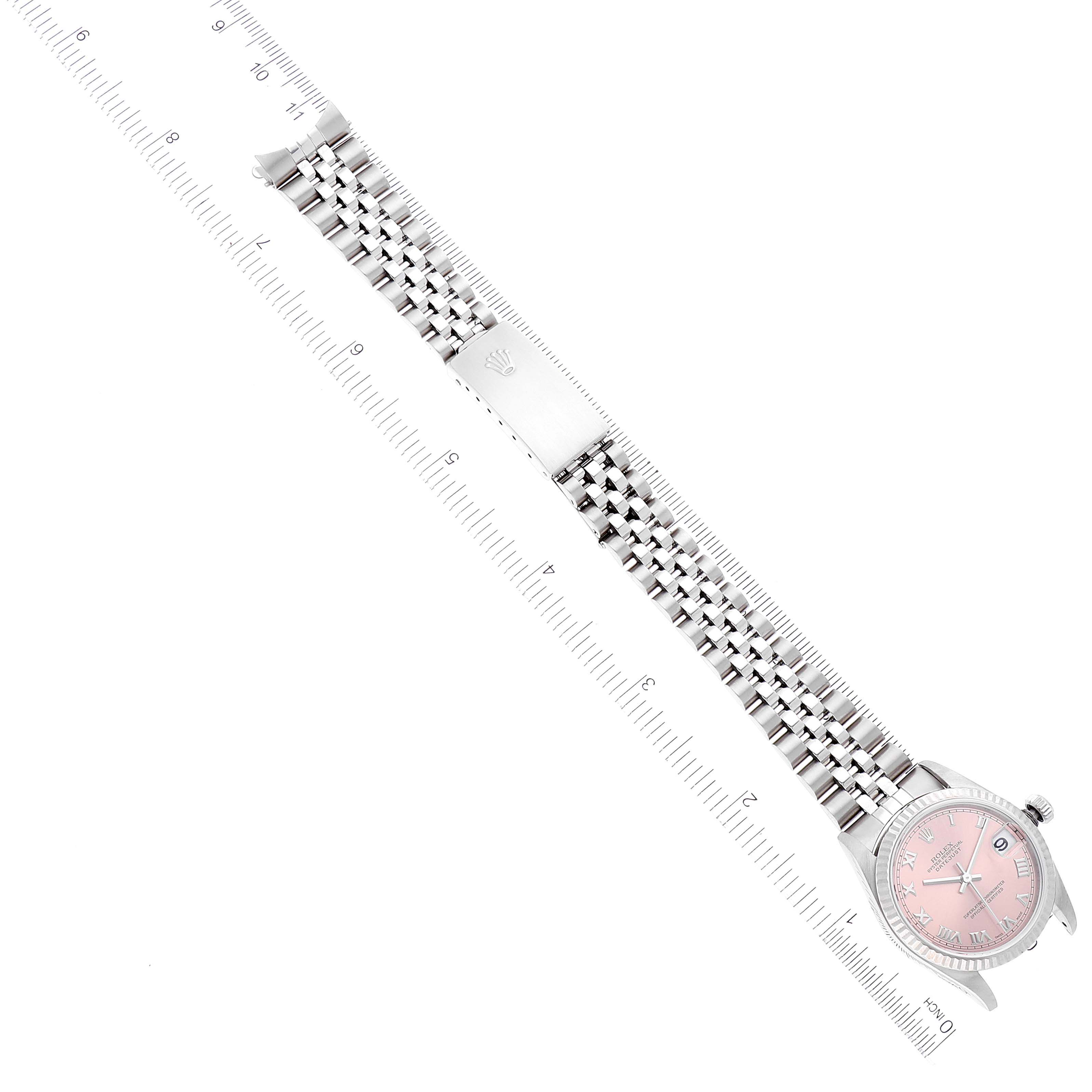 This image shows a top-down view of a Rolex Mid-Size 78274 Women
s Stainless Steel Pink Dial 78274 Women
s Stainless Steel Pink Dial watch with a pink dial and metal bracelet, alongside a ruler.