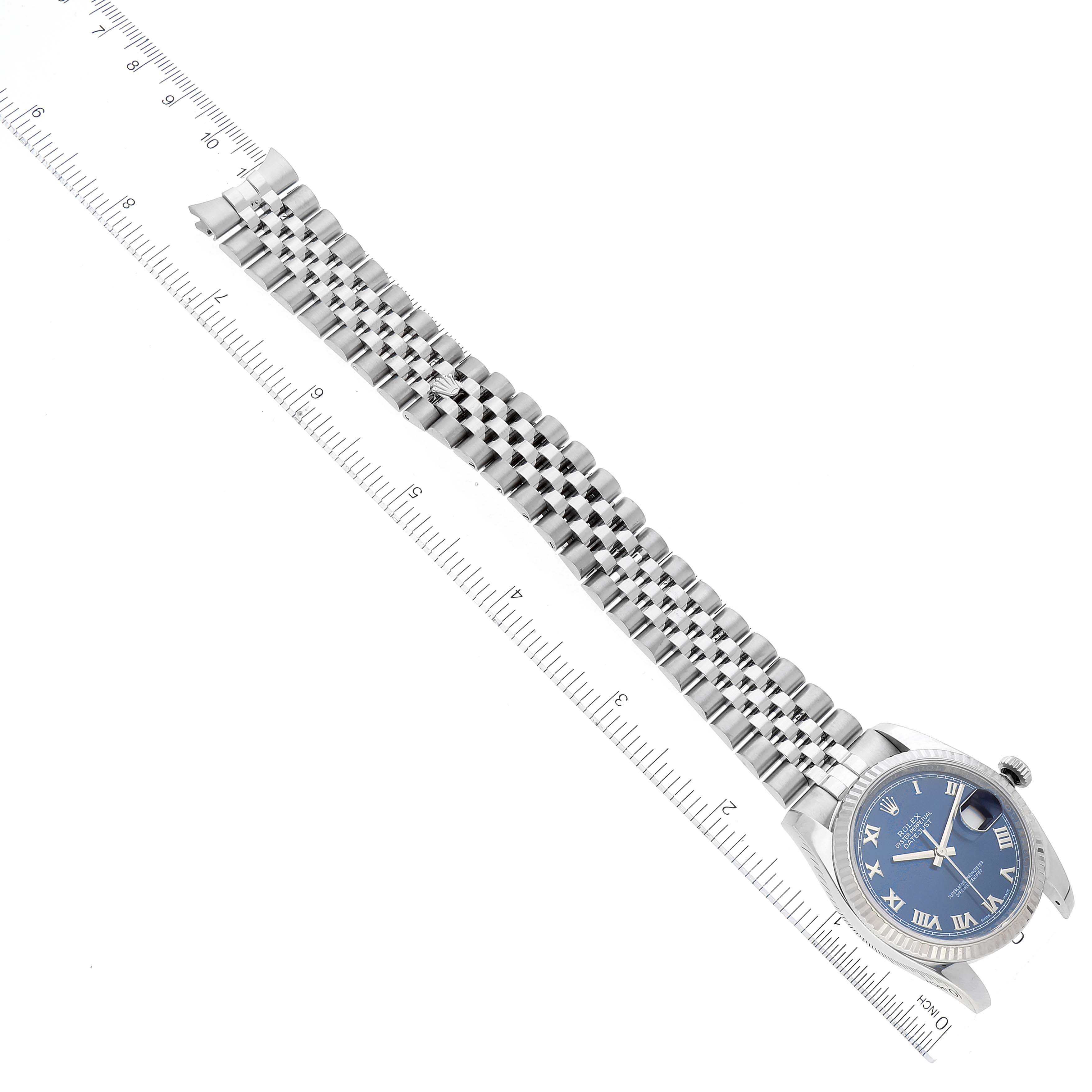 The image shows a Rolex Datejust 116234 Men's Stainless Steel Blue Dial 116234 Men's Stainless Steel Blue Dial watch at an angle, displaying its face, bezel, and full metal bracelet alongside a ruler.