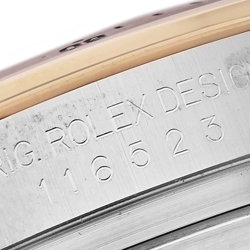 The image shows a close-up of the engraved side of a Rolex Daytona 116523 Men's Steel and Gold (two tone) Silver Dial 116523 Men's Steel and Gold (two tone) Silver Dial watch, highlighting the model number and design inscription.