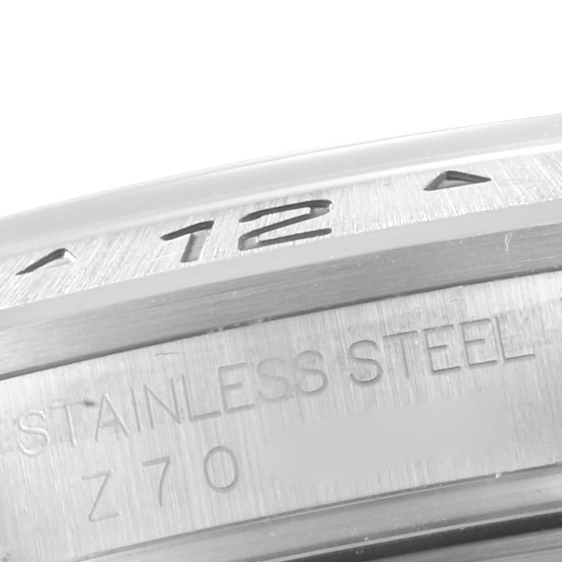 The image shows a close-up of the bezel and part of the case back of a Rolex Explorer 16570 Men's Stainless Steel White Dial 16570 Men's Stainless Steel White Dial model, highlighting the "STAINLESS STEEL" engraving.