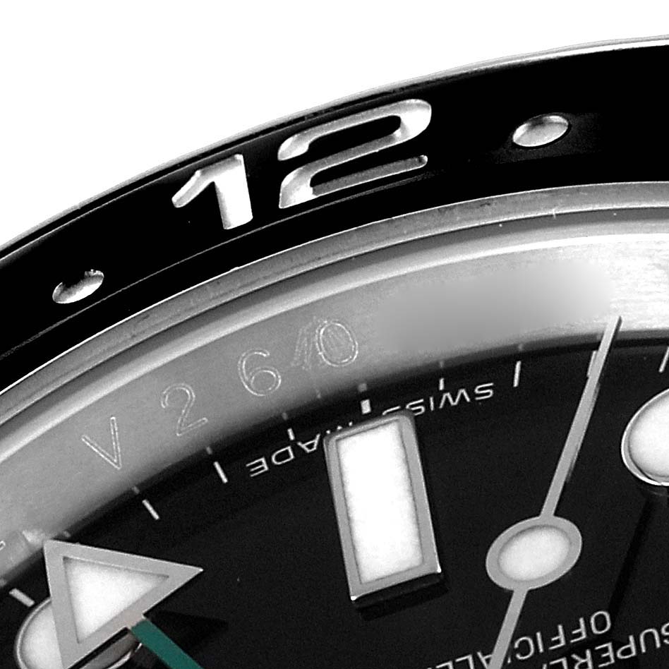 This close-up of the Rolex GMT-Master 116710 Men
s Stainless Steel Black Dial 116710 Men
s Stainless Steel Black Dial watch shows the upper part of the dial, including the 12 o
clock marker, part of the bezel, and some indices.