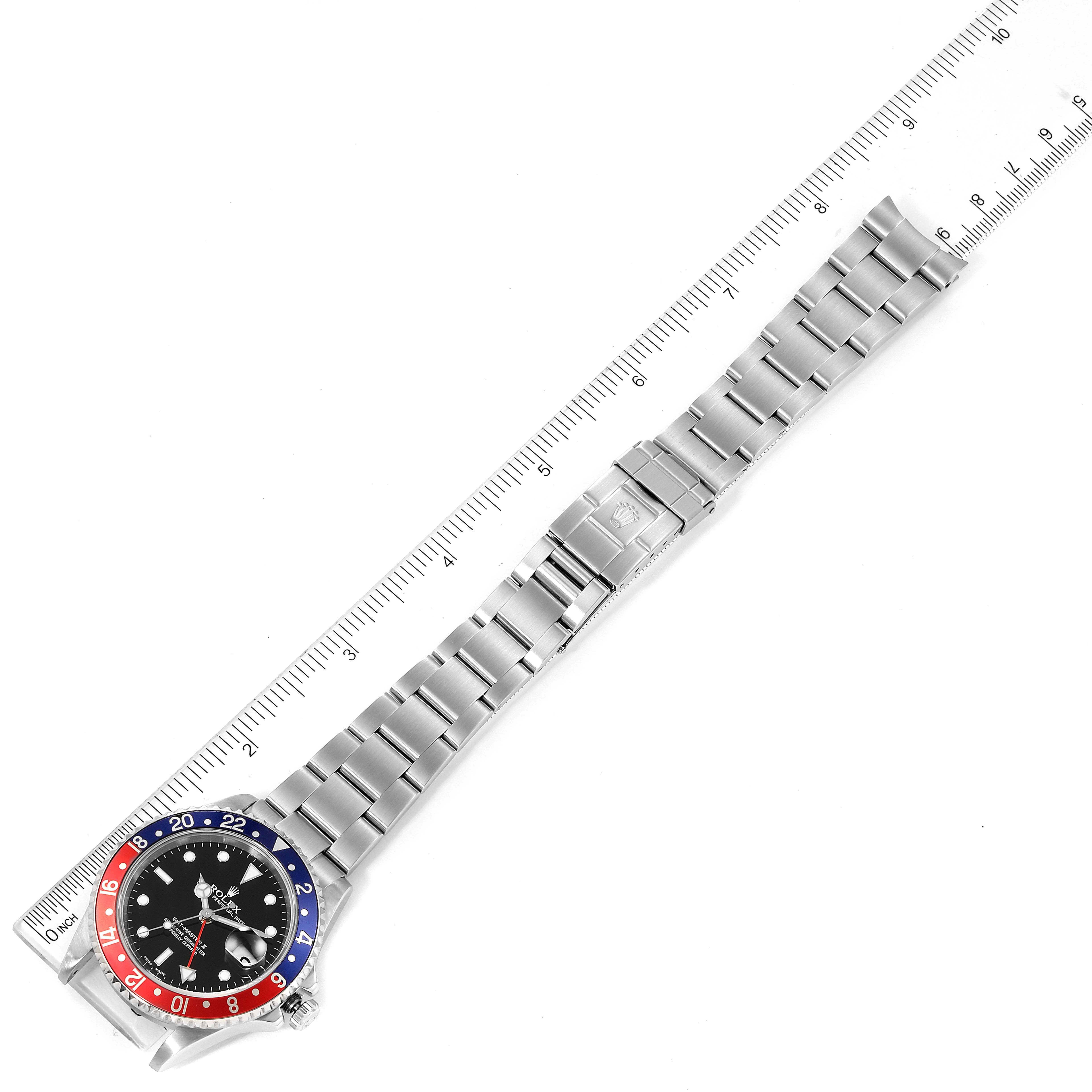 The Rolex GMT-Master 16710 Men
s Stainless Steel Black Dial 16710 Men
s Stainless Steel Black Dial watch is shown from an angled overhead view, displaying the entire watch and its metal bracelet alongside a measuring ruler.