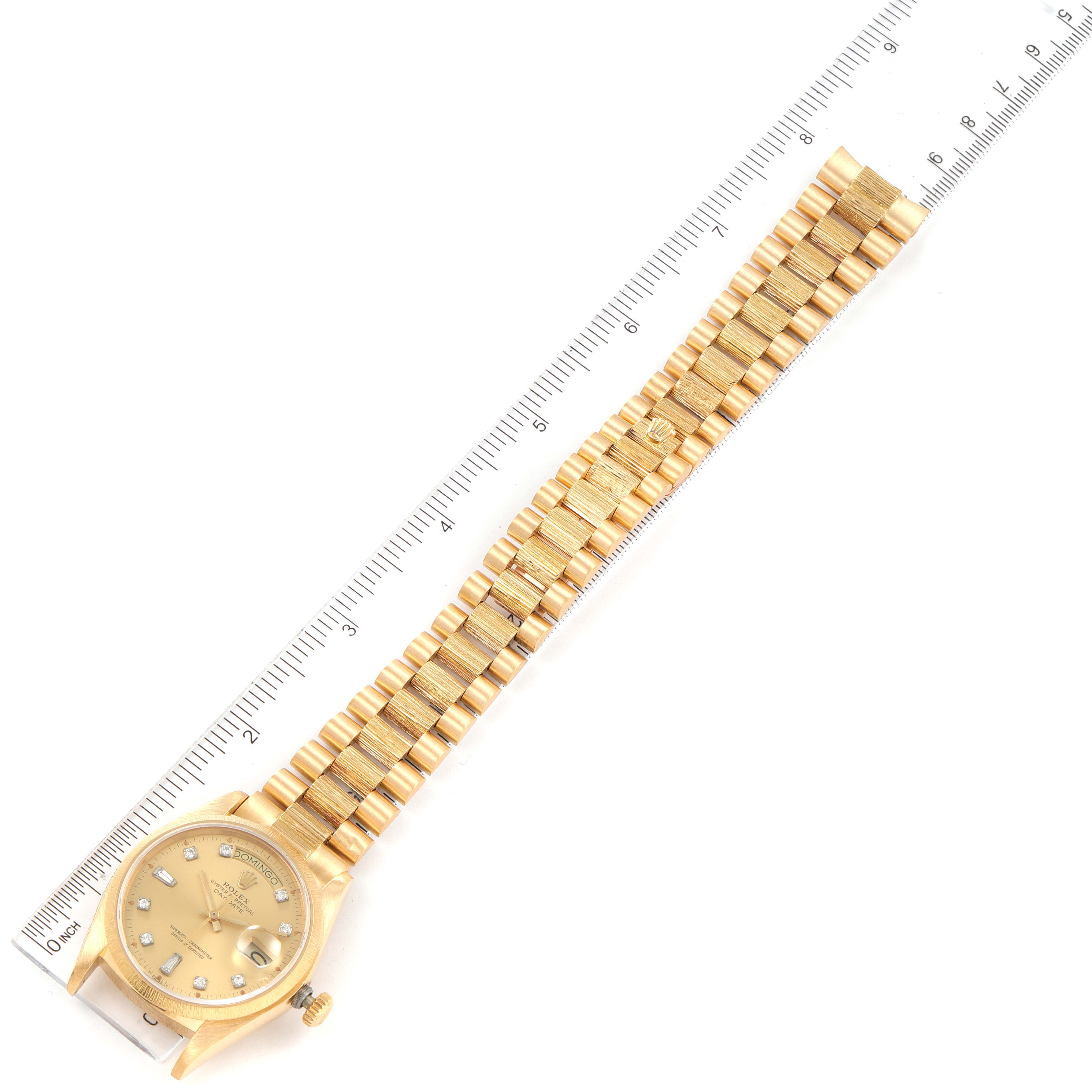 This image shows a top-down view of a gold Rolex President 18078 Men
s Yellow Gold Champagne Dial 18078 Men
s Yellow Gold Champagne Dial watch, including the face, bracelet, and part of the crown, alongside a ruler.