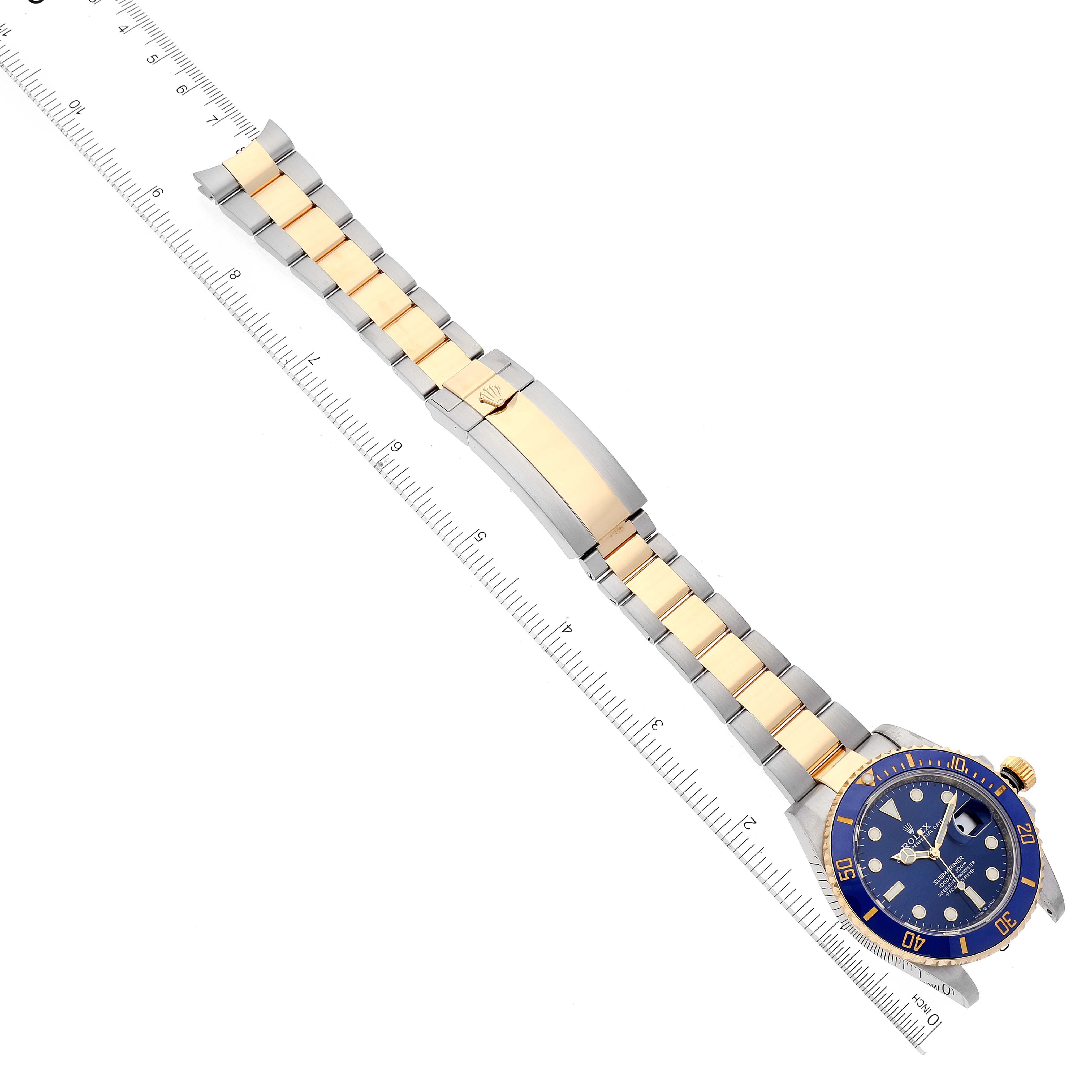 This image shows a top-down view of a Rolex Submariner 126613 Men's Steel and Gold (two tone) Blue Dial 126613 Men's Steel and Gold (two tone) Blue Dial watch, highlighting its face, bezel, and bracelet with a measuring ruler beside it.