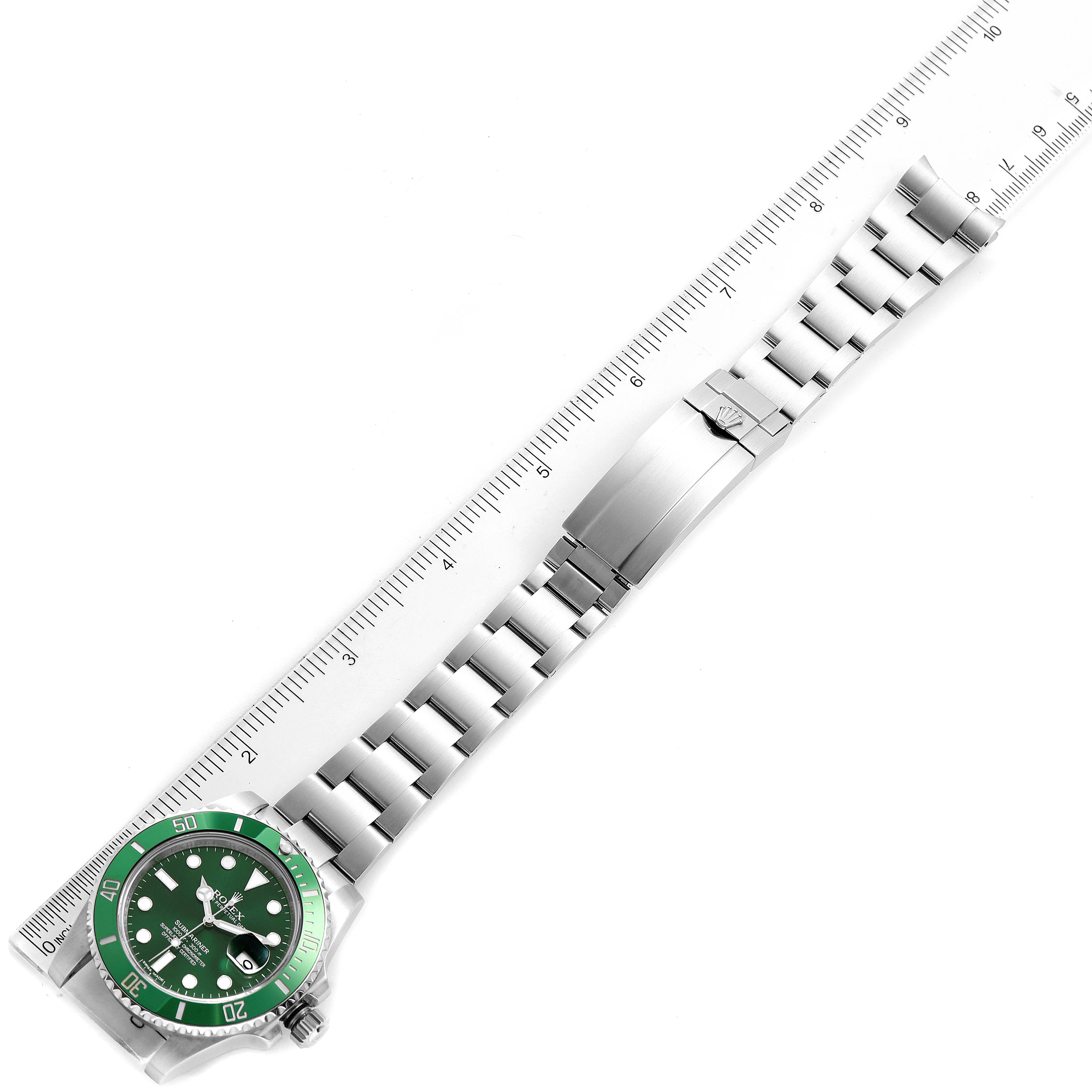 The image shows a Rolex Submariner 116610LV Men
s Stainless Steel Green Dial 116610LV Men
s Stainless Steel Green Dial watch with a green bezel and dial, laid flat beside a ruler to measure its length.