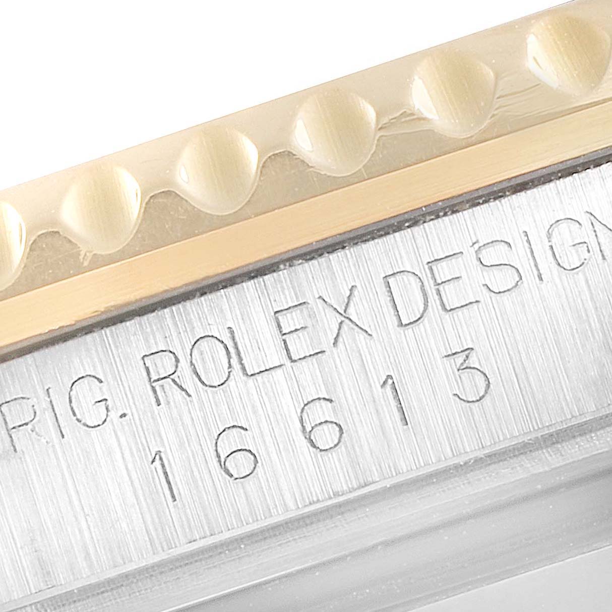 This close-up image of a Rolex Submariner 16613 Men's Steel and Gold (two tone) Black Dial 16613 Men's Steel and Gold (two tone) Black Dial shows the edge of the bezel and the engraved case with model number 16613.