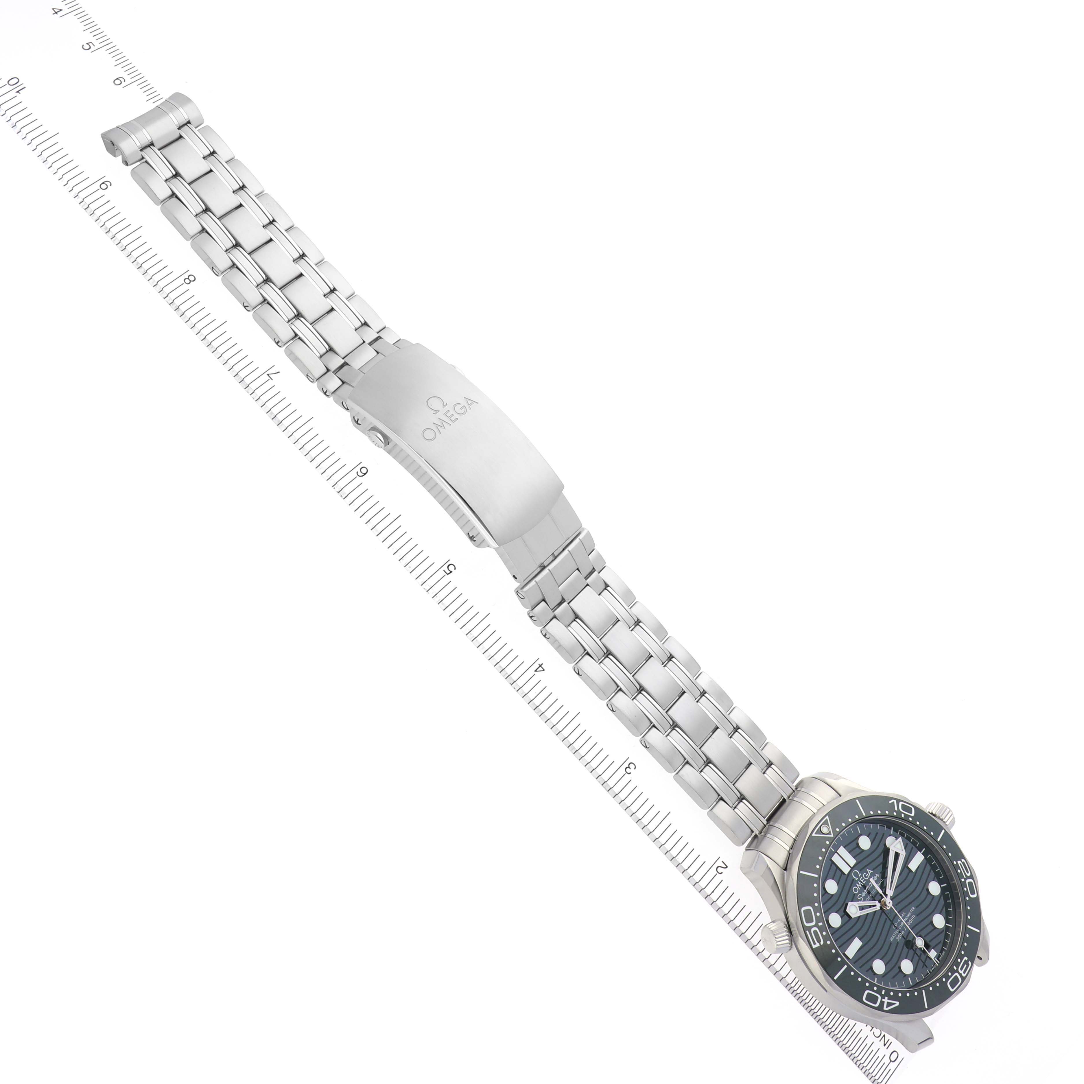 The Omega Seamaster 210.30.42.20.10.001 Men's Stainless Steel Green Dial 210.30.42.20.10.001 Men's Stainless Steel Green Dial watch is shown from a top-down angle, displaying its full metal bracelet and clasp alongside a scale measurement.