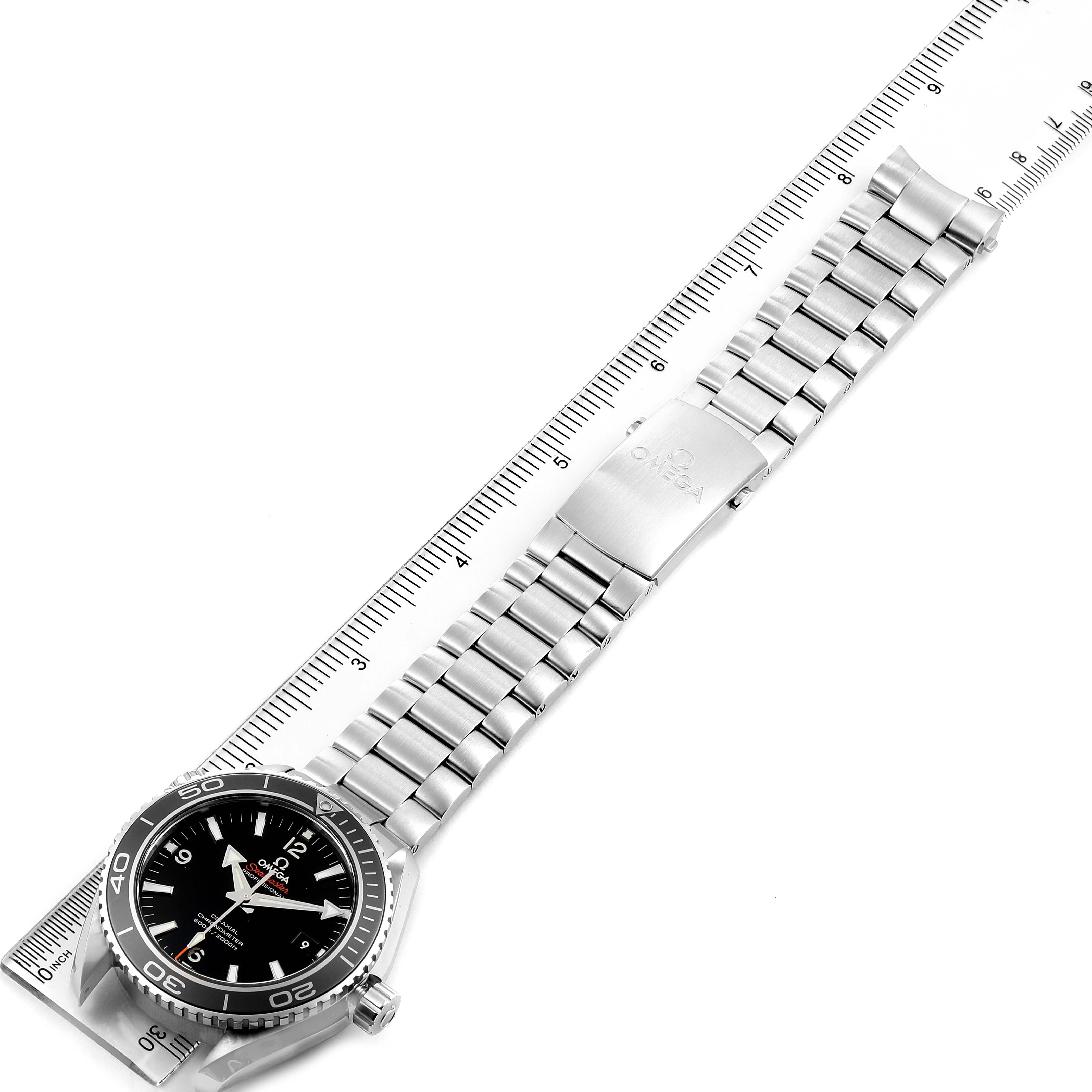 This image shows an overhead view of an Omega Planet Ocean 232.30.46.21.01.001 Men
s Stainless Steel Black Dial 232.30.46.21.01.001 Men
s Stainless Steel Black Dial watch, showcasing the entire face, case, and metal bracelet against a measuring ruler.