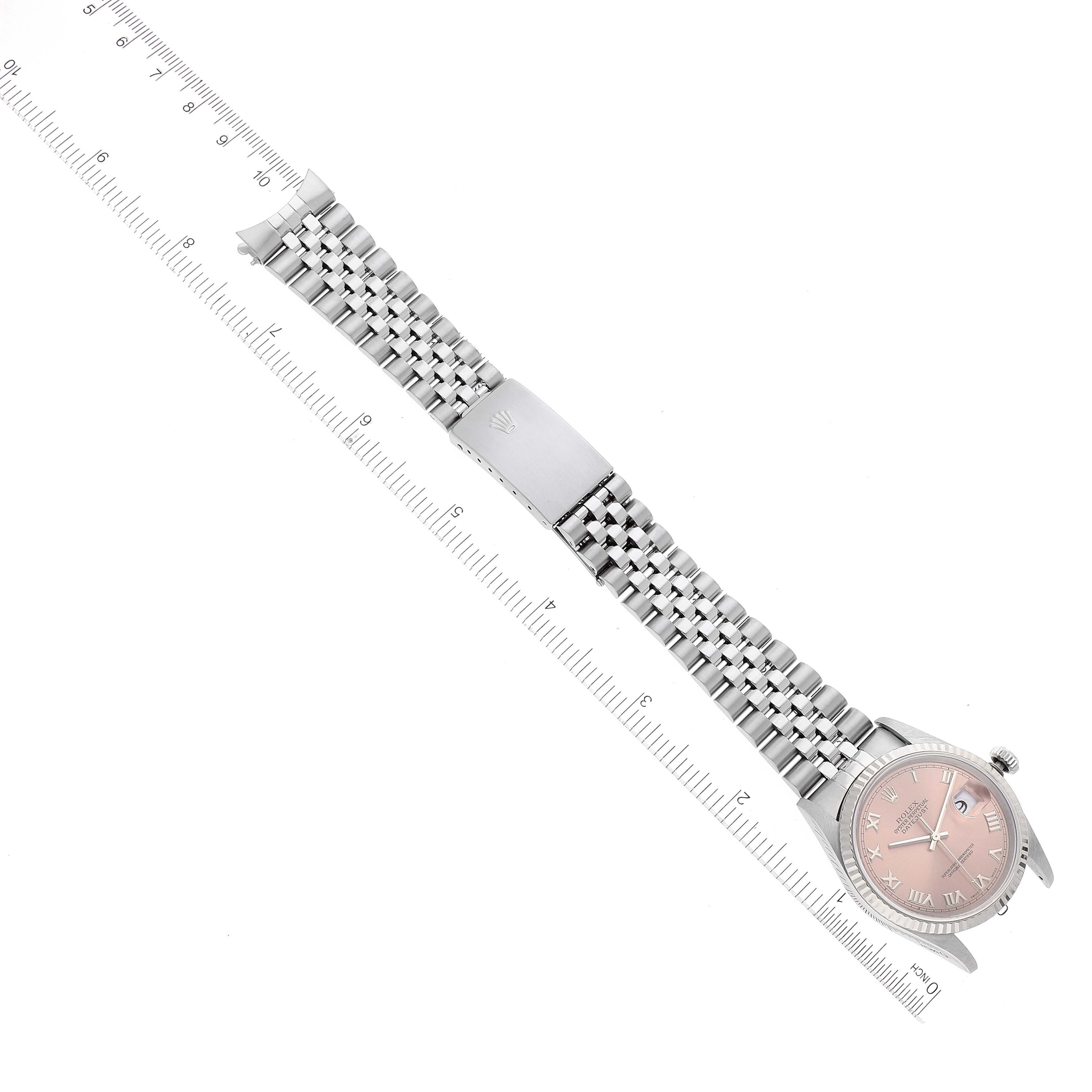 The Rolex Datejust 16234 Men
s Stainless Steel Pink Dial 16234 Men
s Stainless Steel Pink Dial watch is shown from an overhead angle, displaying the dial, bracelet, and clasp alongside a measuring scale.