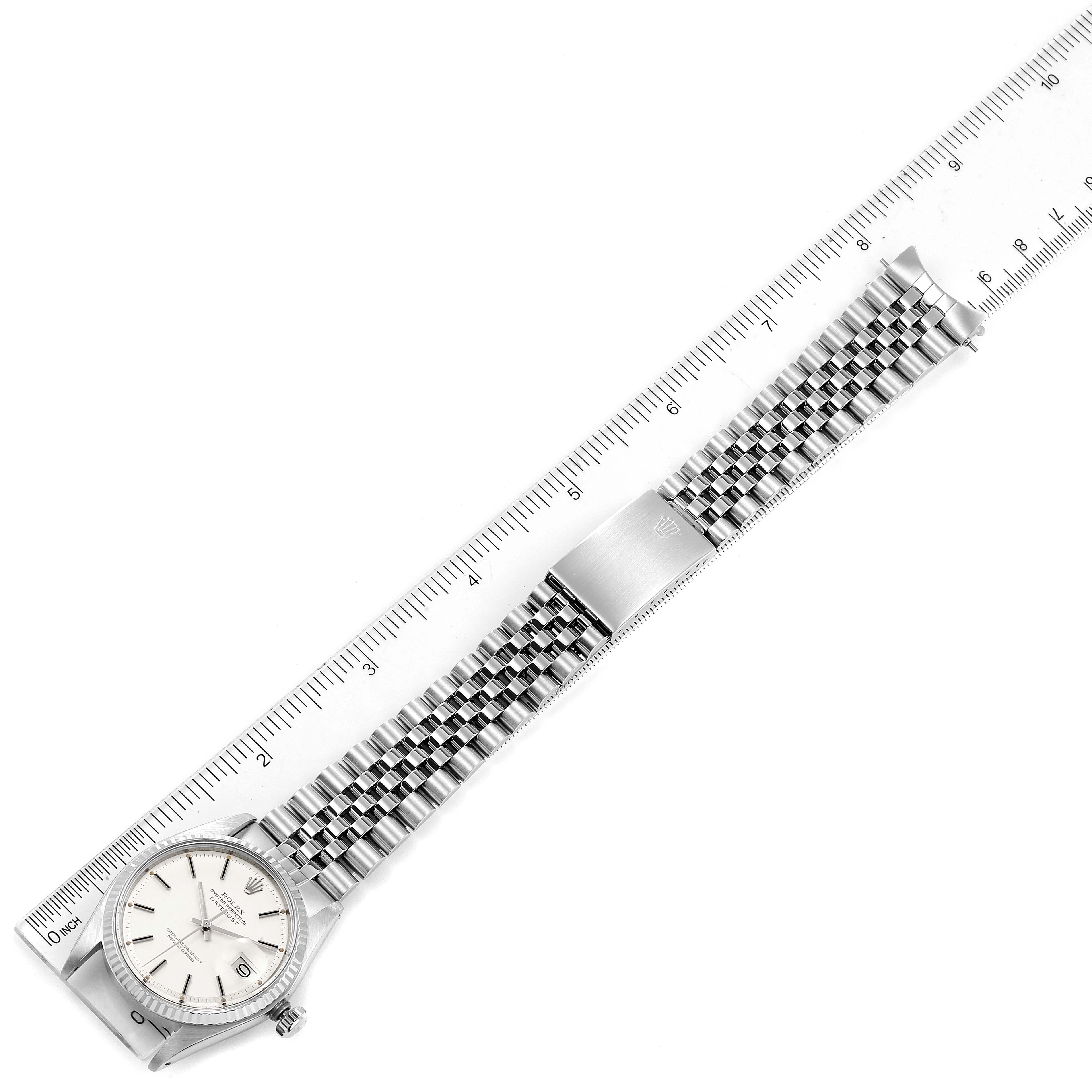 The image shows a top-down view of the Rolex Vintage Collection 1601 Men's Stainless Steel Silver Dial 1601 Men's Stainless Steel Silver Dial watch, featuring its face and metal bracelet alongside a ruler for scale.