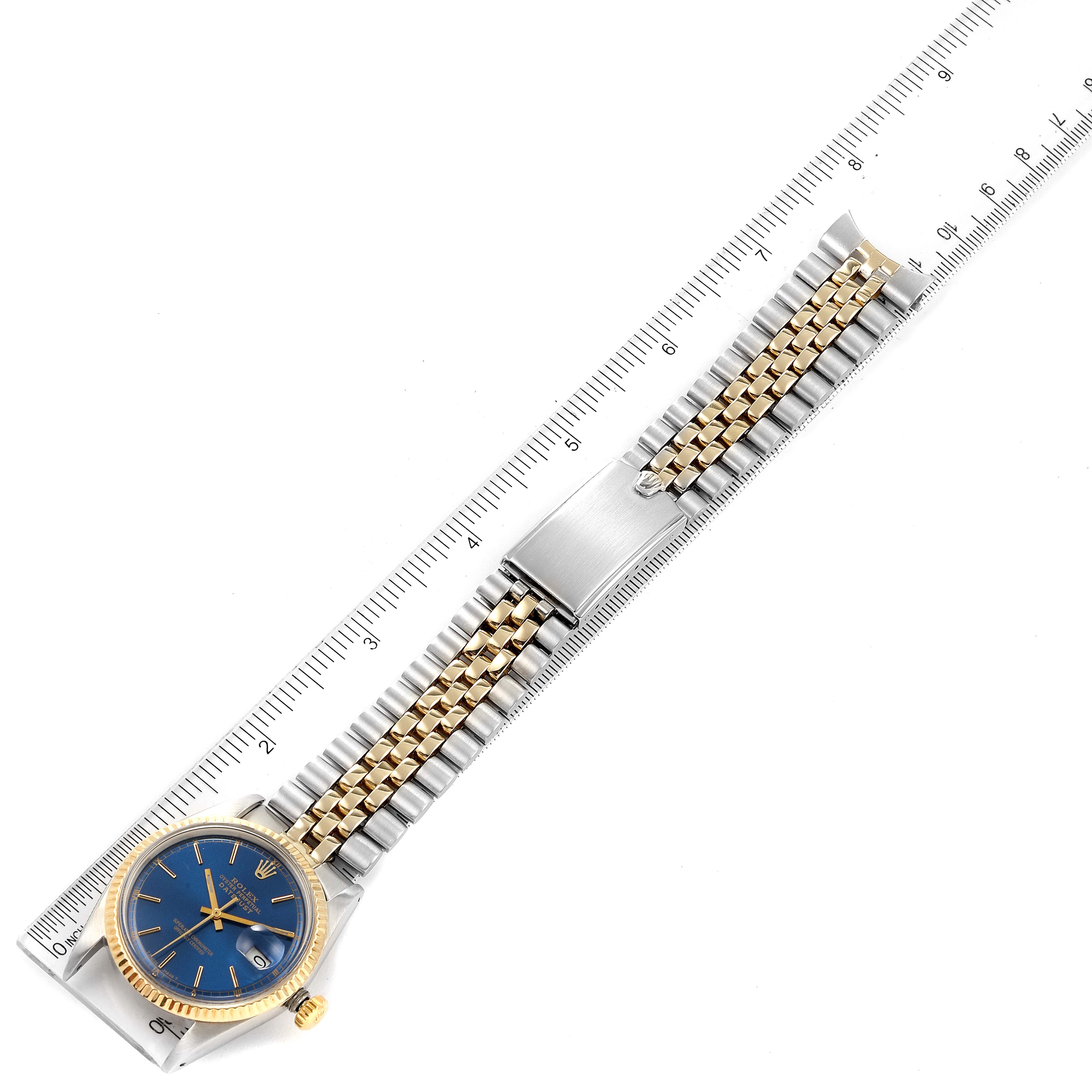 The Rolex Vintage Collection 1601 Men's Steel and Gold (two tone) Blue Dial 1601 Men's Steel and Gold (two tone) Blue Dial watch is shown flat with its blue dial, gold bezel, two-tone bracelet, and clasp visible, alongside a ruler.