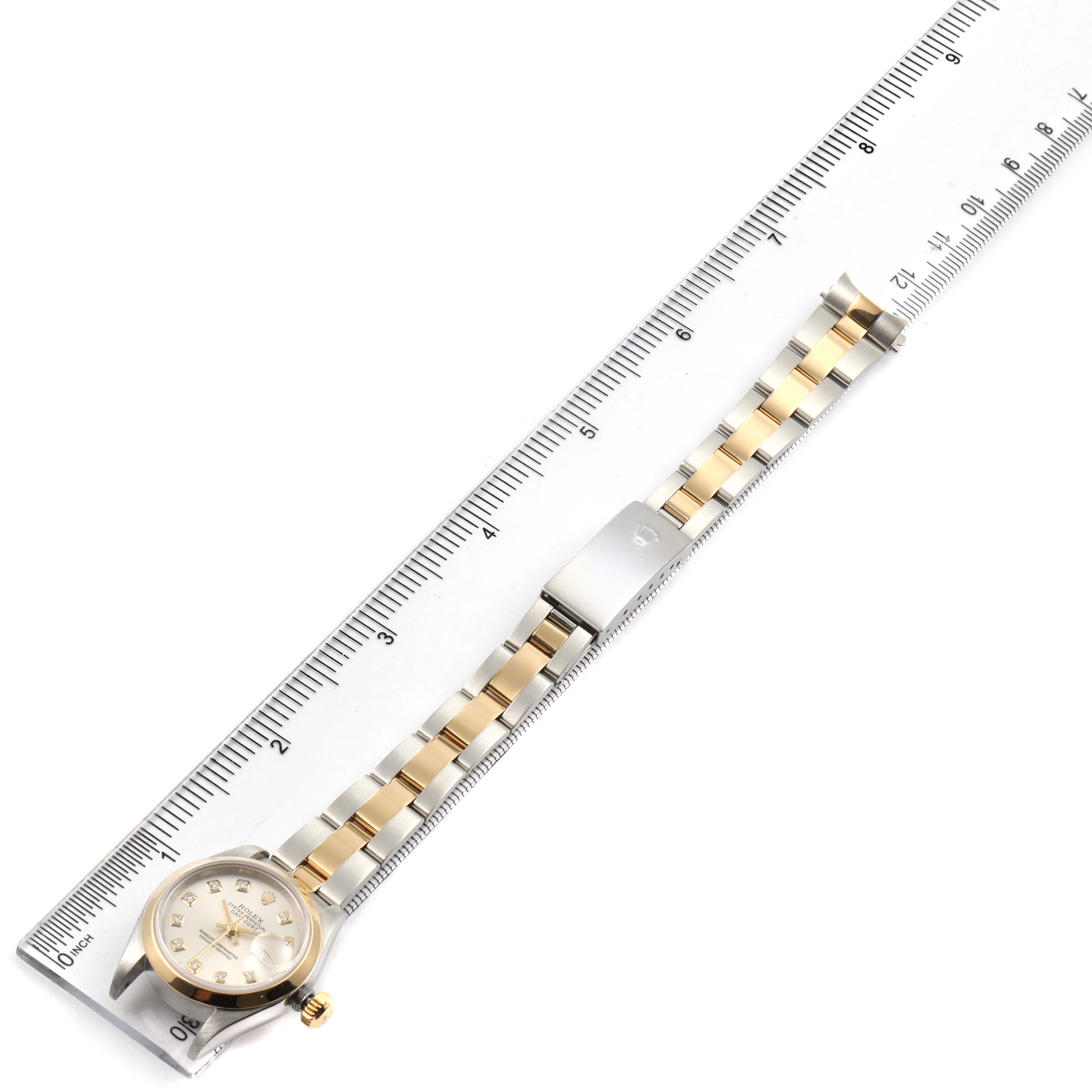 The image shows a Rolex Datejust 79163 Women's Steel and Gold (two tone) Silver Dial 79163 Women's Steel and Gold (two tone) Silver Dial watch laid flat alongside a ruler, focusing on the face, bracelet, and clasp.