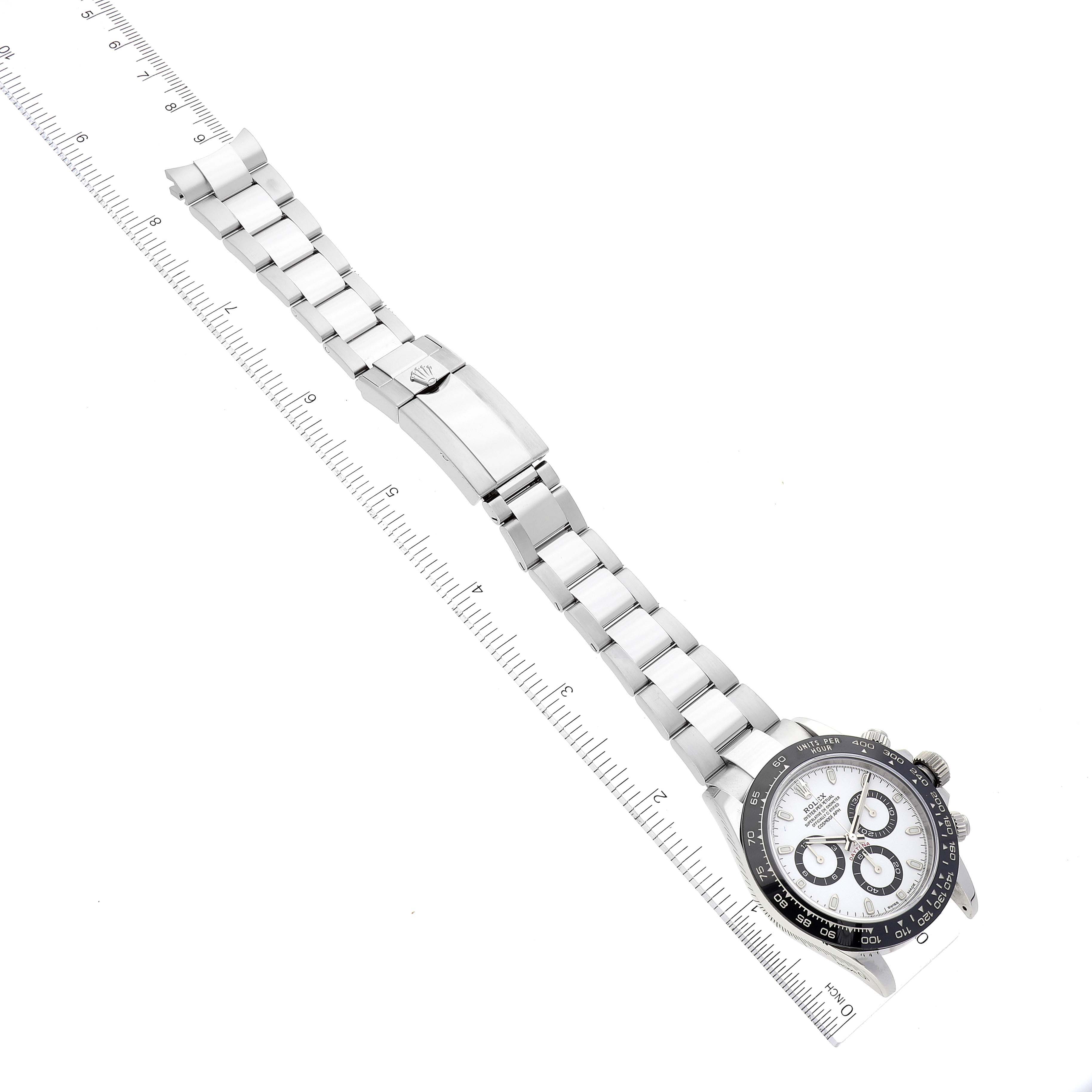 The image shows the Rolex Daytona 116500 Men's Stainless Steel White Dial 116500 Men's Stainless Steel White Dial watch laid flat, featuring its bracelet, clasp, and face, next to a ruler for size reference.