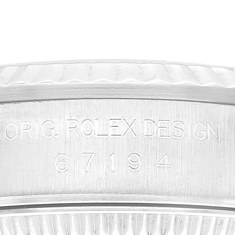 This image shows a close-up of the engraved serial number and "ROLEX" branding on the case of a Rolex Oyster Perpetual 67194 Women's Stainless Steel White Dial 67194 Women's Stainless Steel White Dial watch.