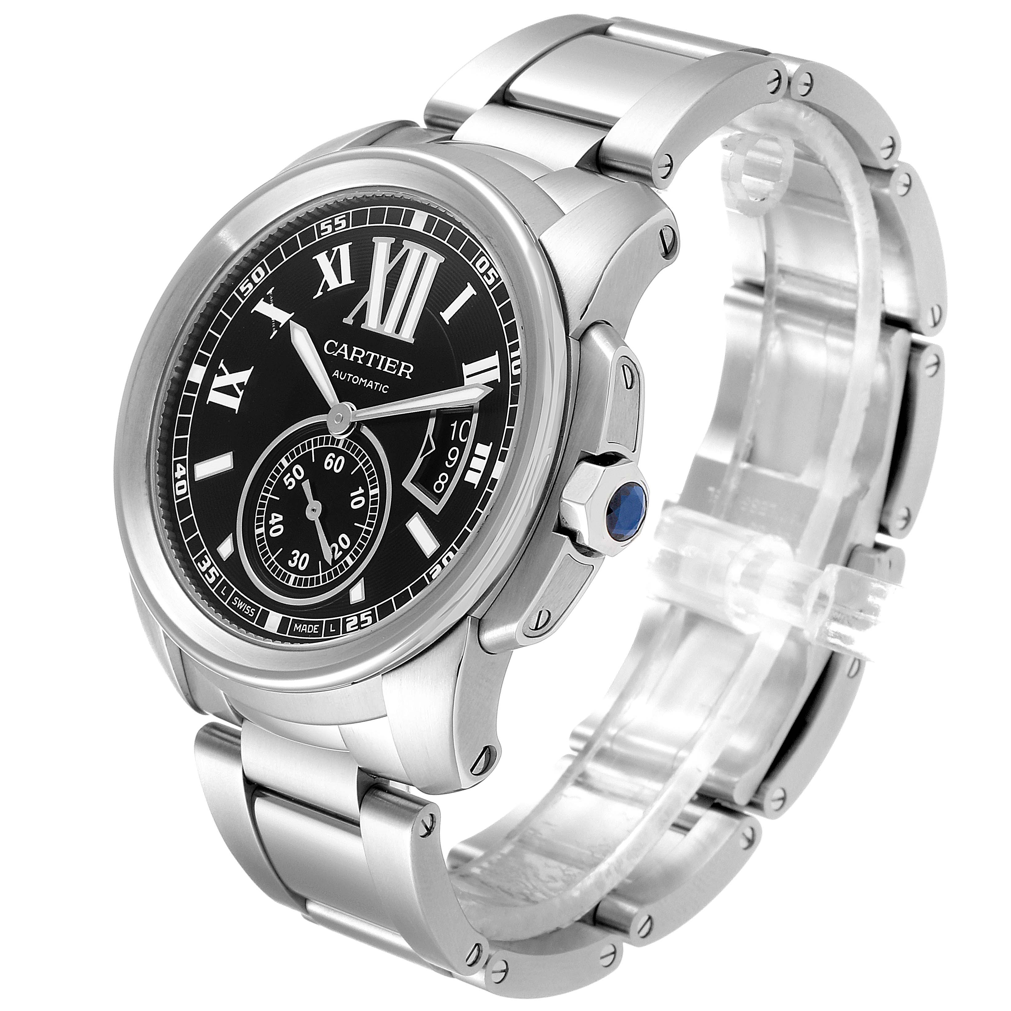 The image shows a front angled view of the Calibre de Cartier watch by Cartier, displaying its black dial, metal bracelet, and crown with a blue gem.