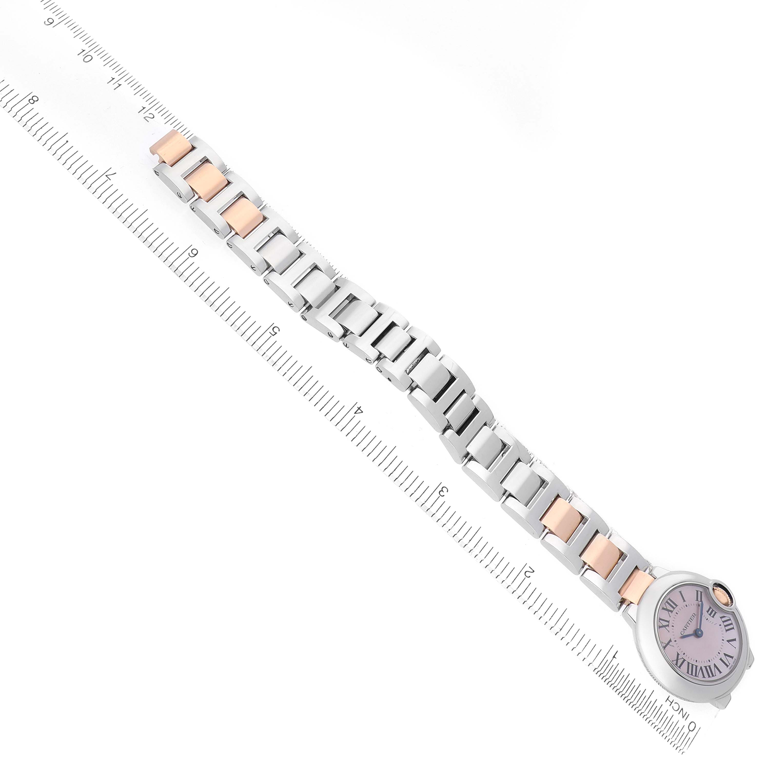 The Cartier Ballon Bleu W6920034 Women's Steel and Gold (two tone) Mother of Pearl Dial watch is shown from above, displaying its two-tone bracelet and round face next to a ruler for scale.